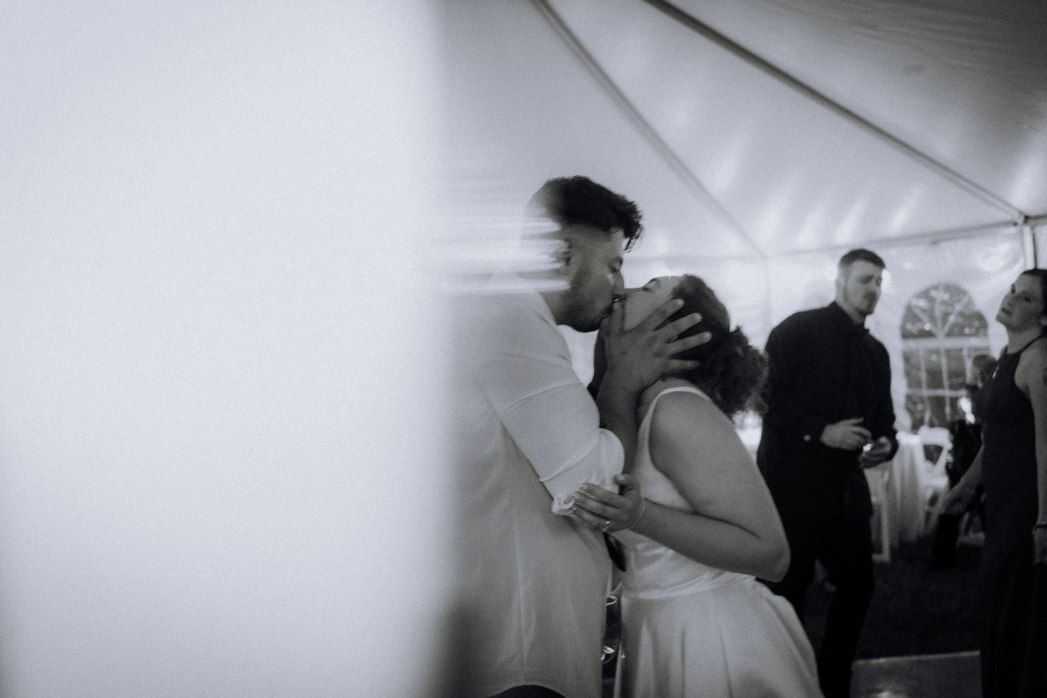 Wedding reception guests dancing and celebrating in black and white photography.