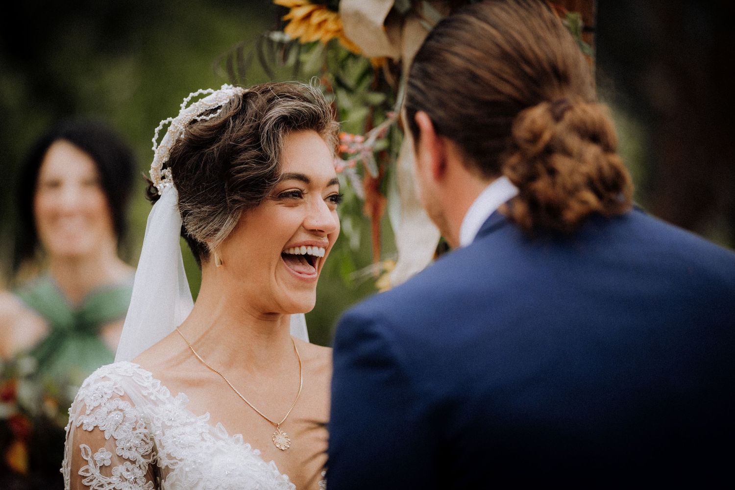 Joyful wedding moment captured with autumn-colored bouquet and lace details.