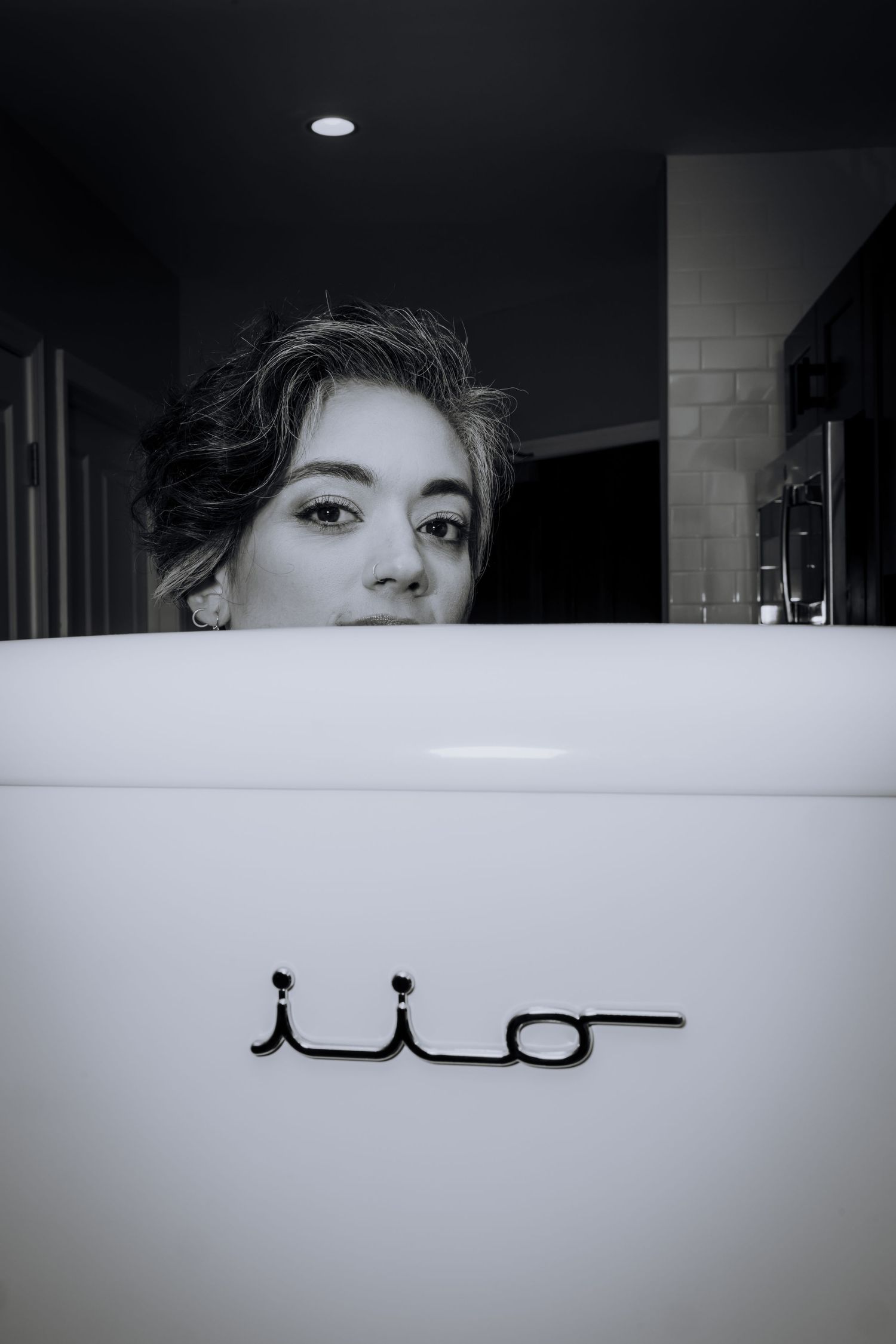 Artistic black and white bathroom mirror selfie with Arabic text below.