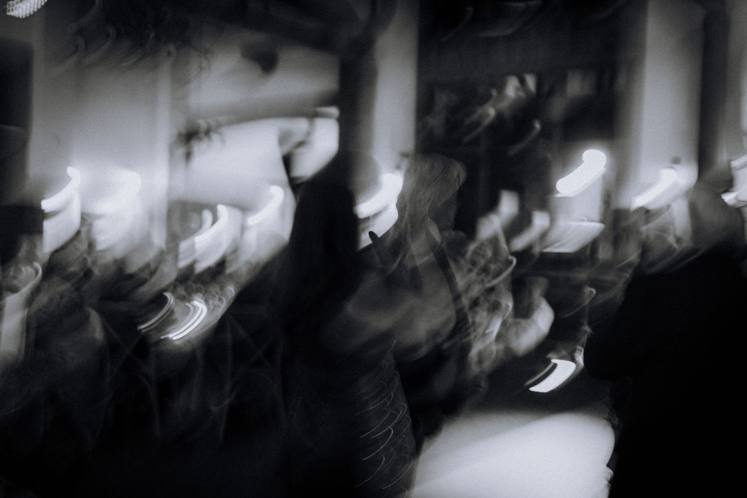 A black and white artistic shot of people dancing at a wedding reception.