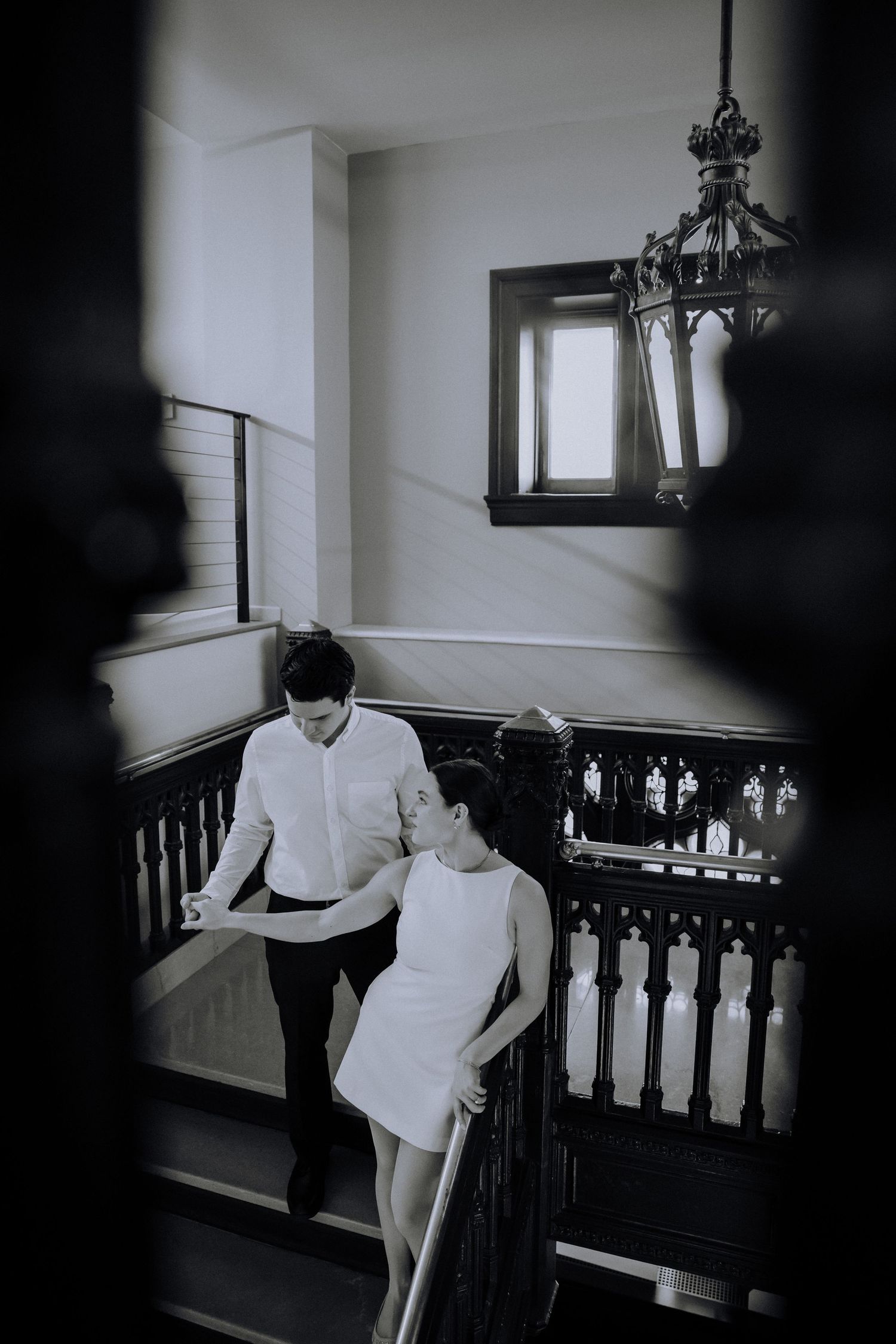 Black and white wedding photography in a venue with ornate wooden railings.