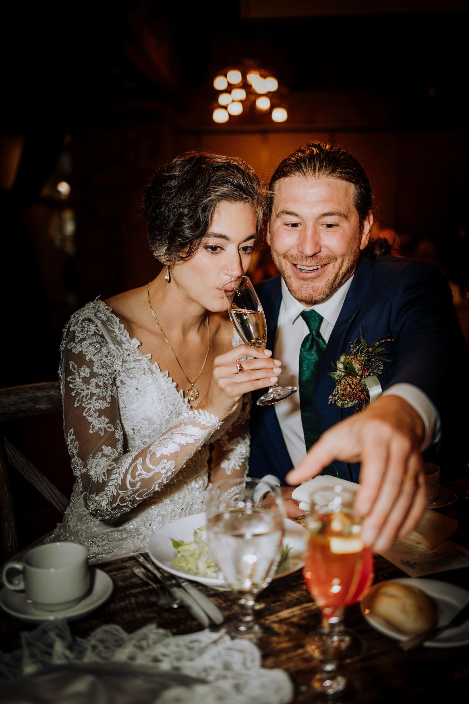 A couple shares an intimate moment while dining at their wedding reception with candlelit ambiance.