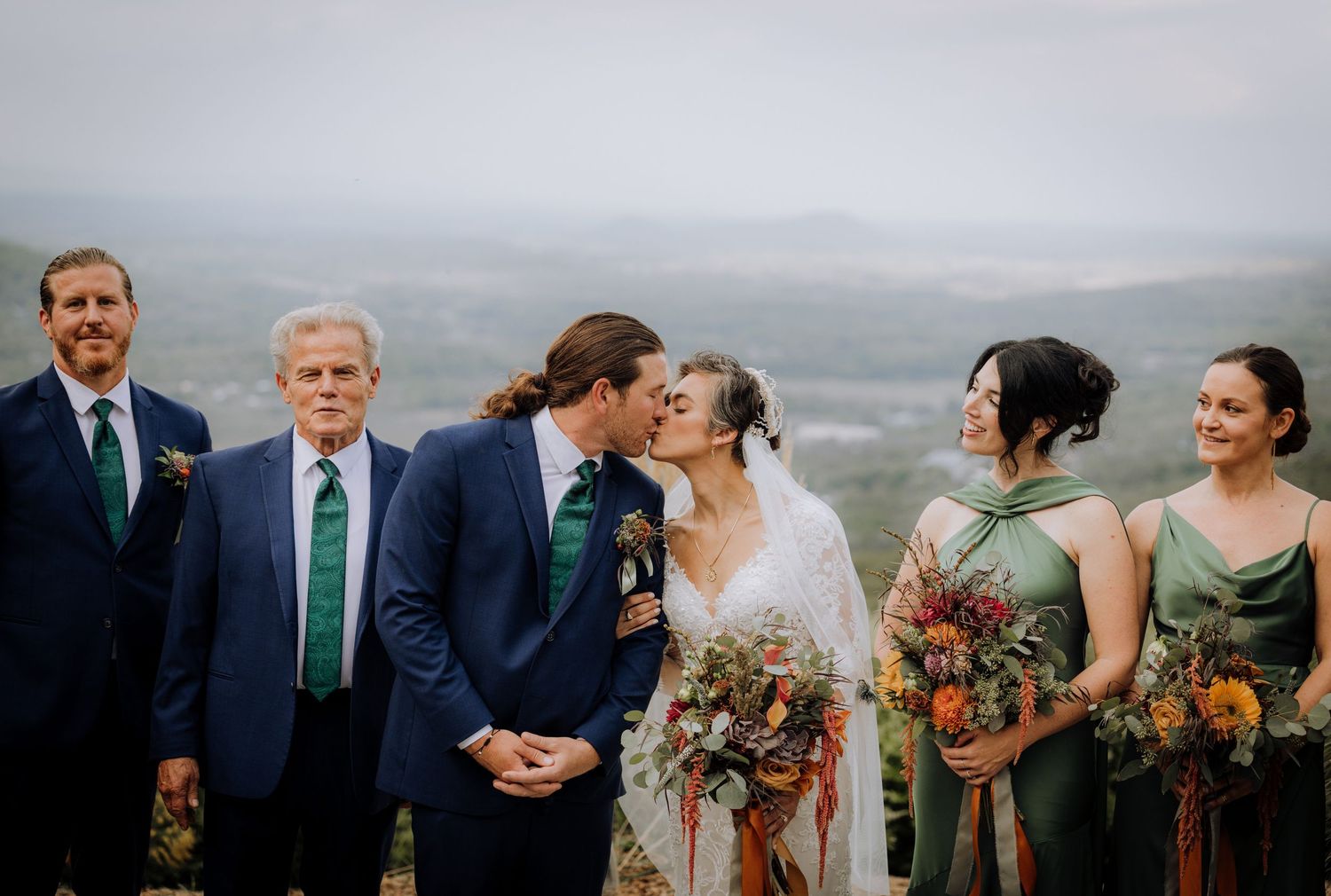 Wedding party lined up on mountain overlook during autumn ceremony.
