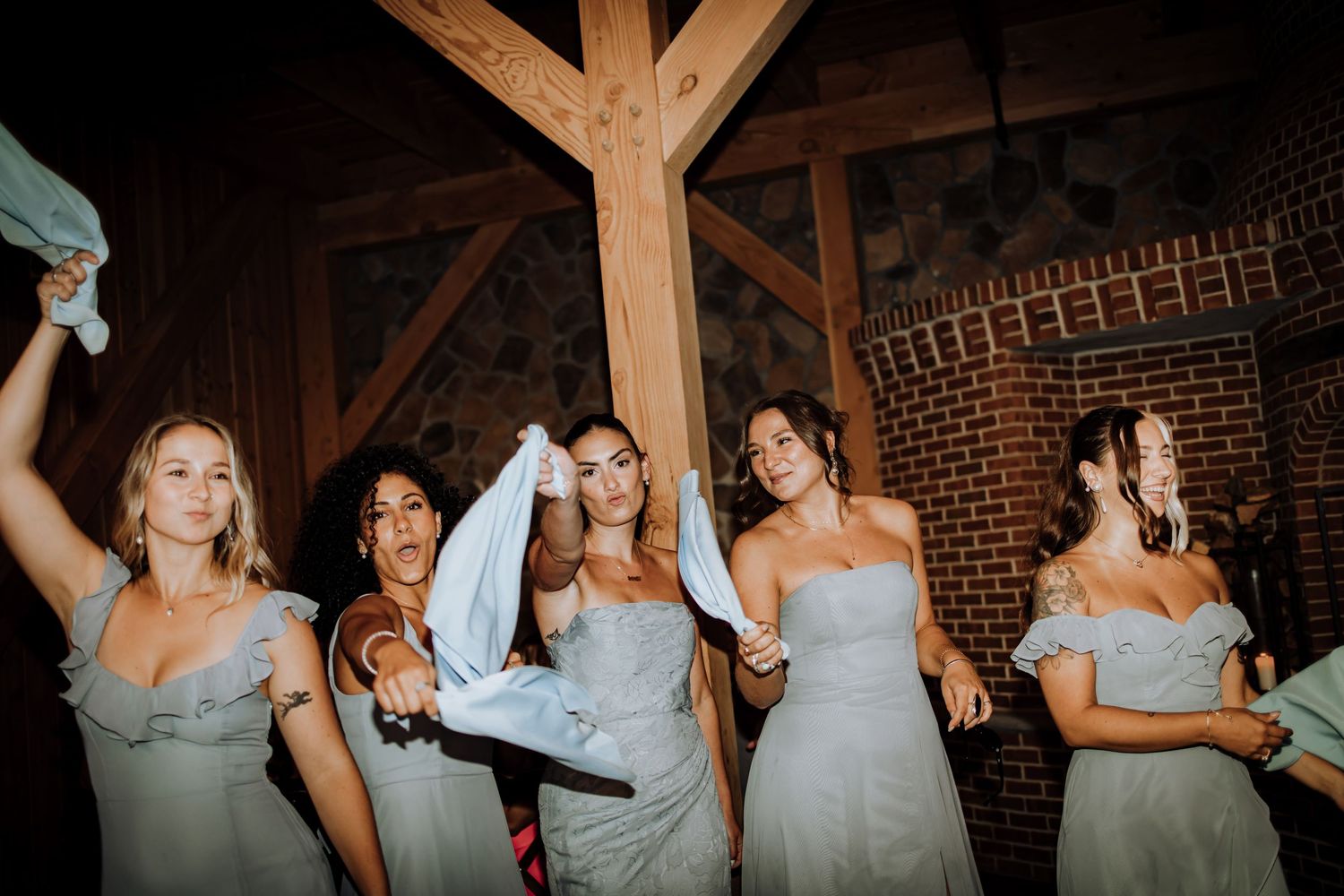 Wedding party dancing and celebrating in a rustic wooden venue.