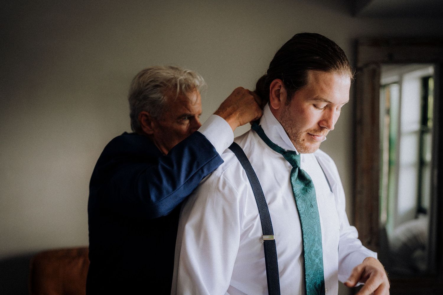 A person adjusts their formal attire while getting ready for a special event.