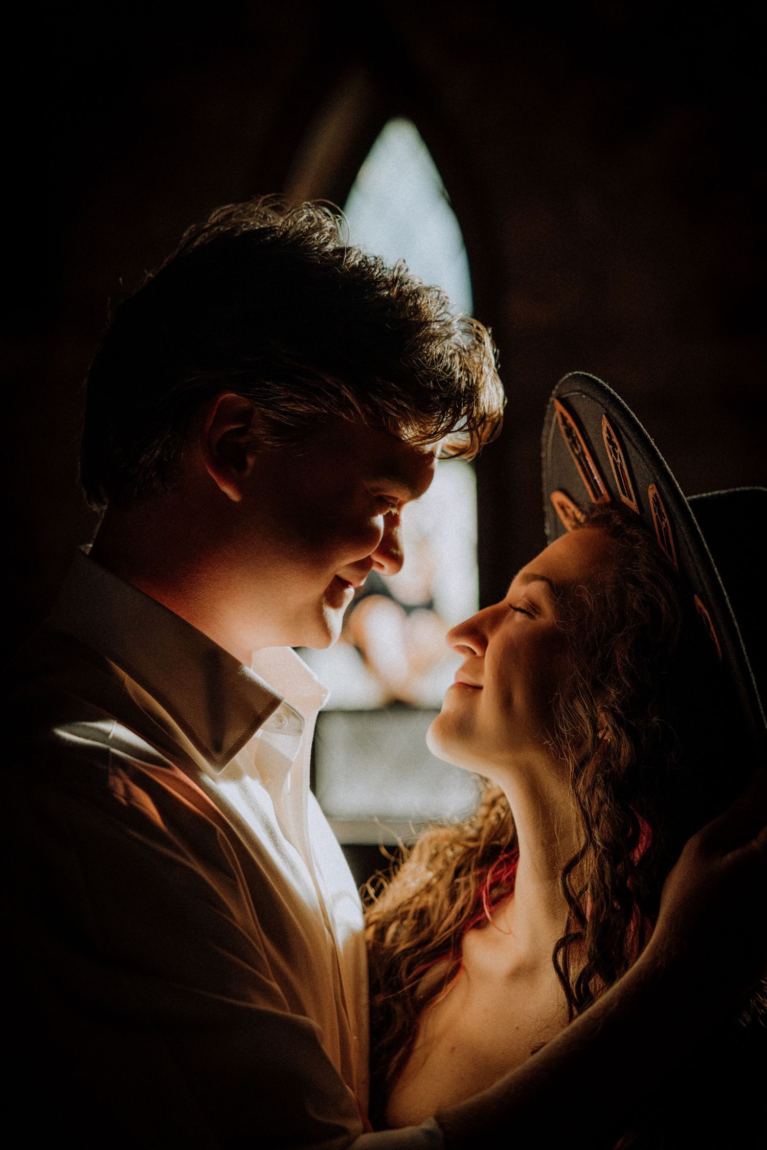 Intimate portrait in dramatic lighting showing a tender moment against a dark background.