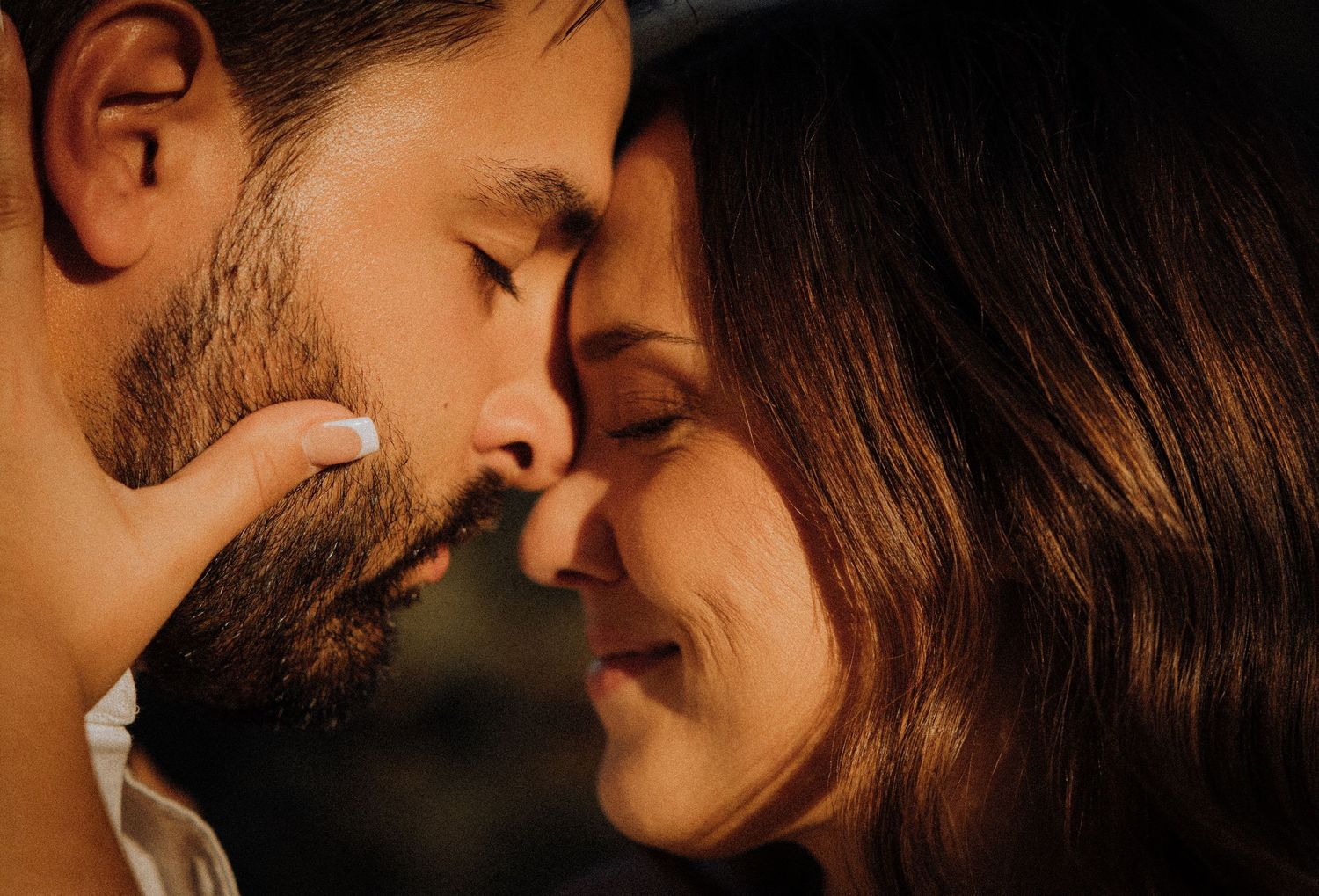 An intimate close-up portrait of a couple sharing a tender moment at golden hour.