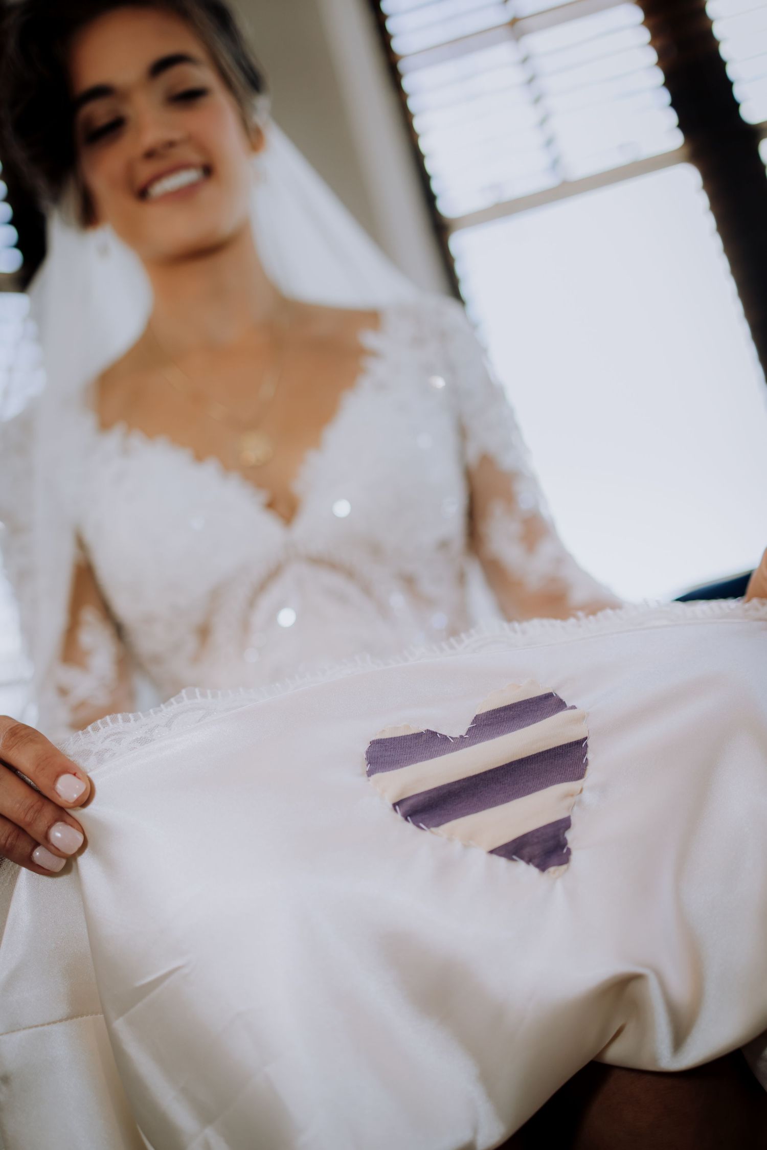 Wedding dress detail showing a purple heart design on white fabric.