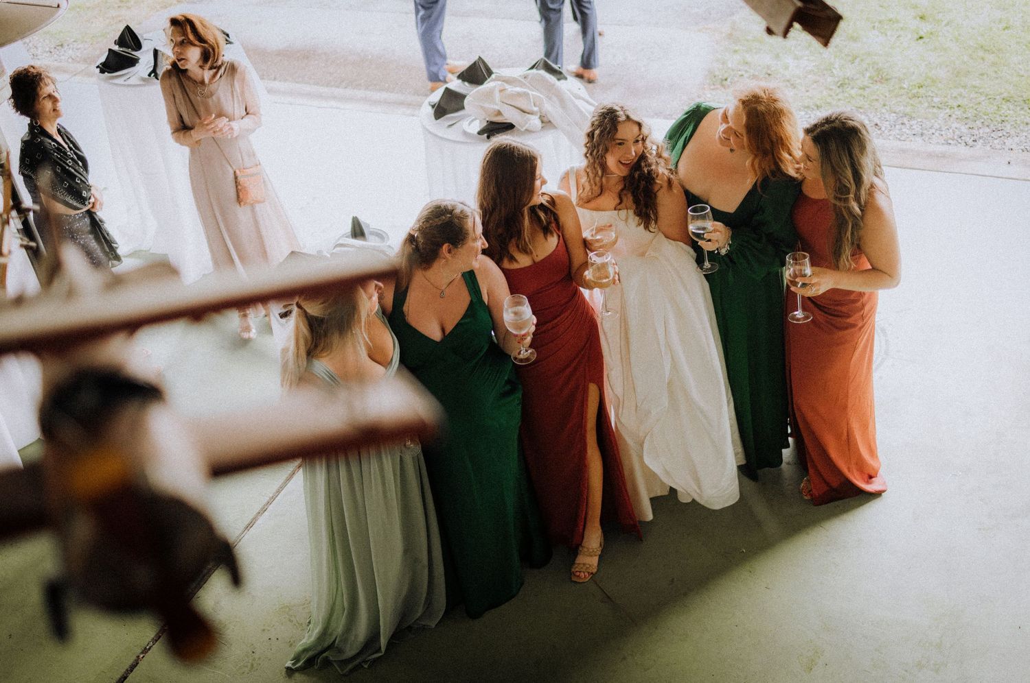 Wedding party in colorful dresses gathered outdoors during celebration.
