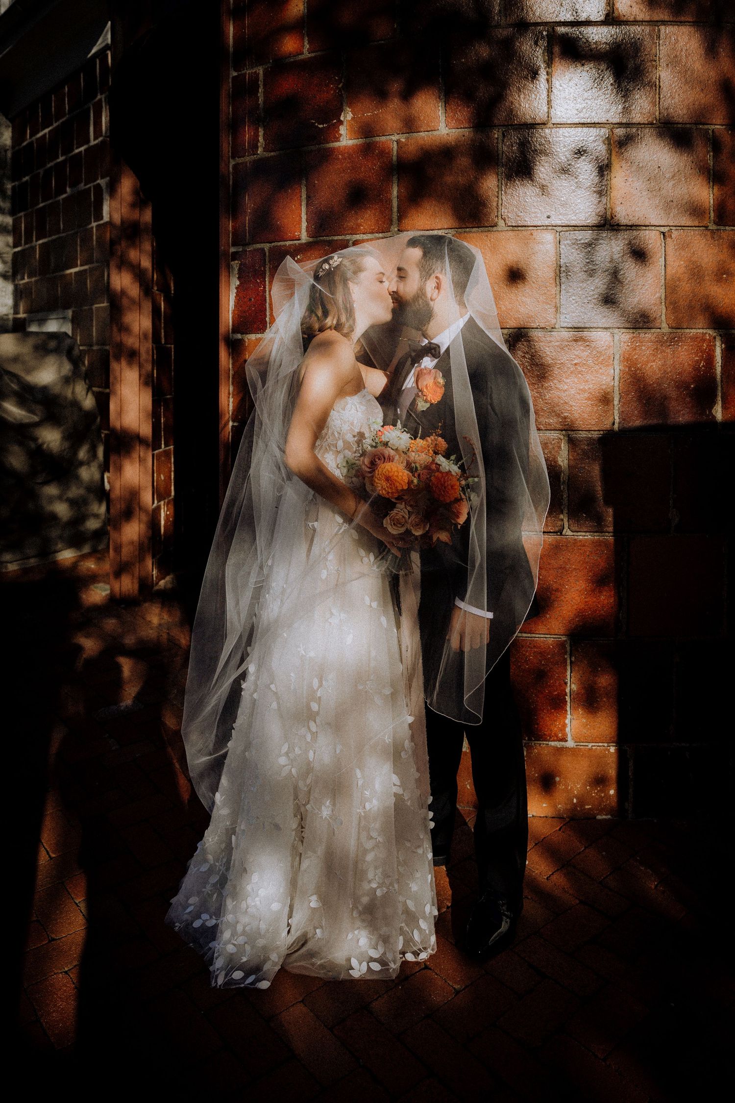 Artistic shadows play across brick walls as wedding couple poses for portraits.