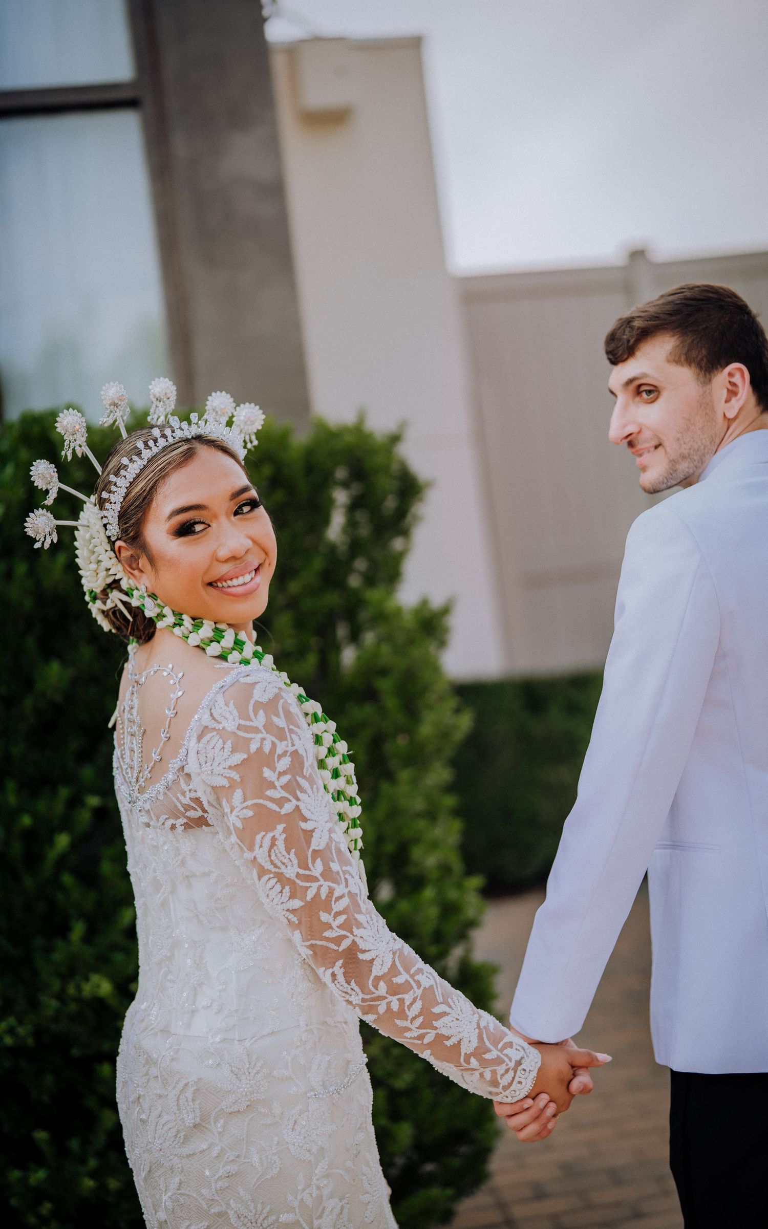 Bride in delicate lace wedding gown with long sleeves poses for romantic photos outdoors during wedding photoshoot.