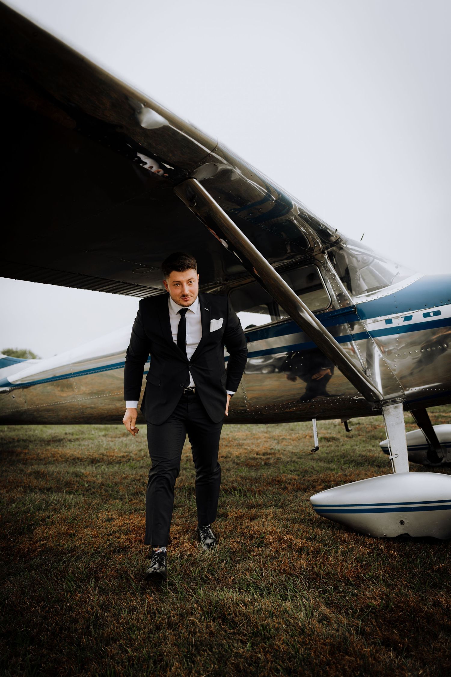A private airplane sits on a grassy field during a moody overcast day.