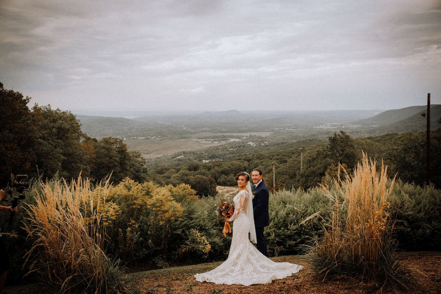 Scenic mountain wedding venue with golden grass and winding road in the distance.