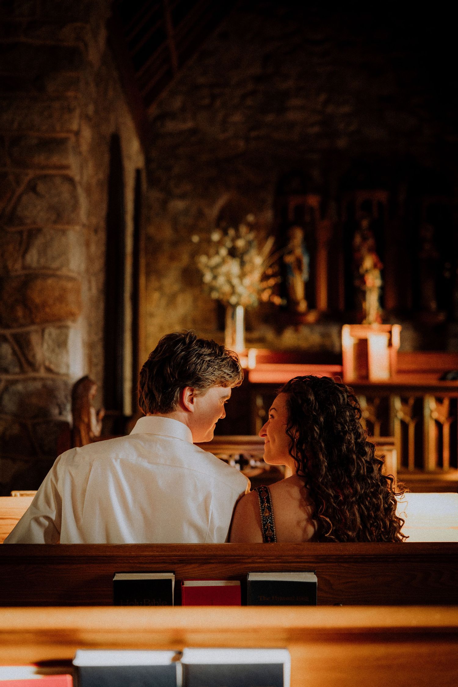 A romantic moment captured in a dimly lit church with warm candlelight creating an intimate atmosphere.