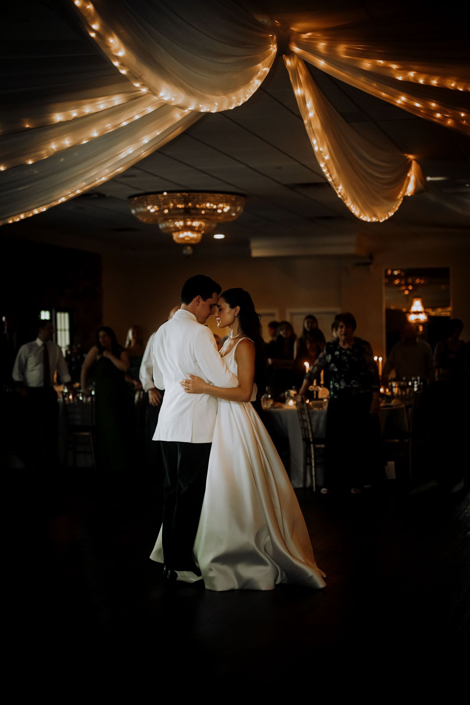Wedding reception under a tent with string lights creating a romantic ambiance in the dark.