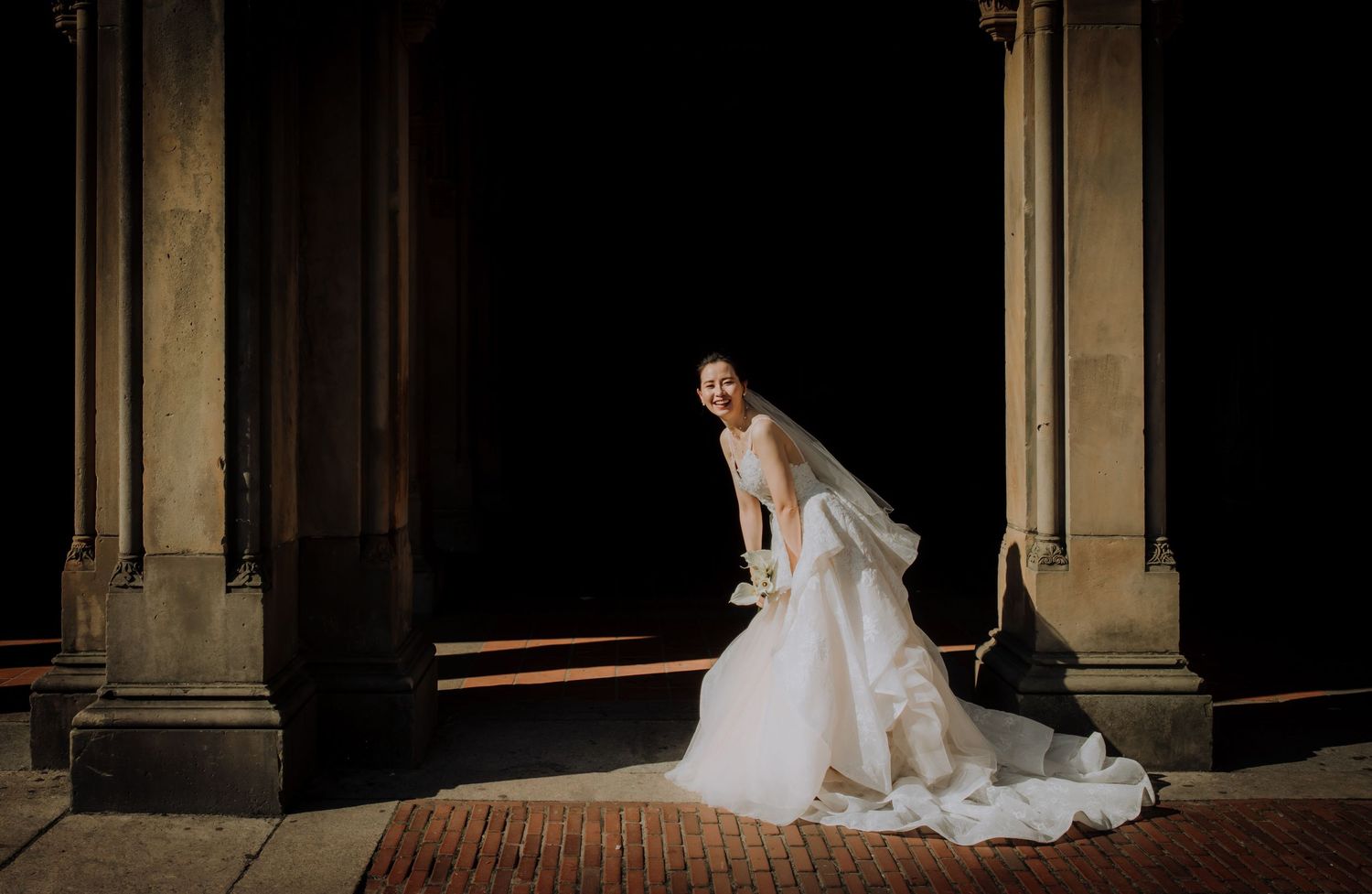 Dramatic architectural columns frame a wedding scene in dark lighting.