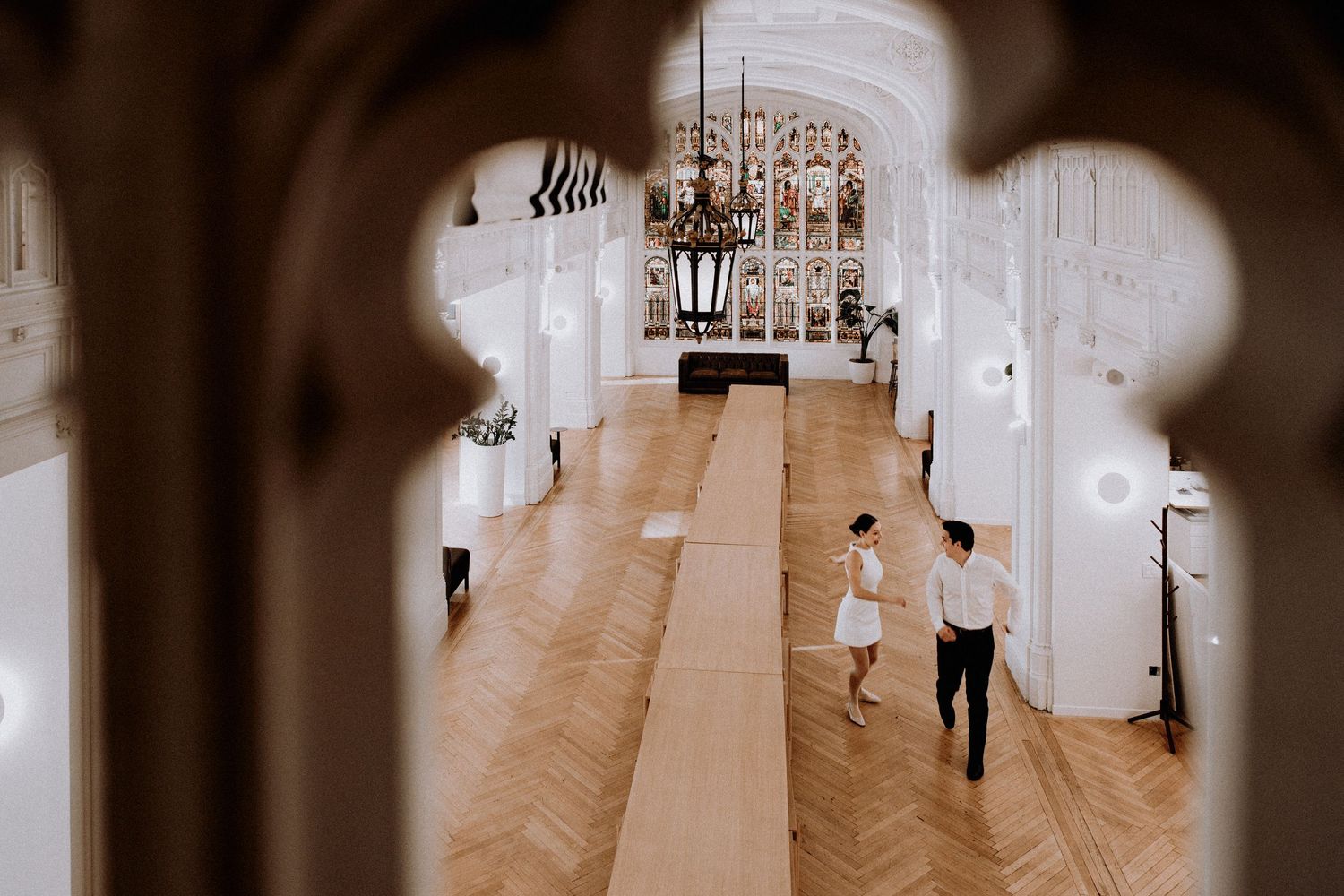 Long hallway with elegant chandeliers and white walls in a wedding venue.