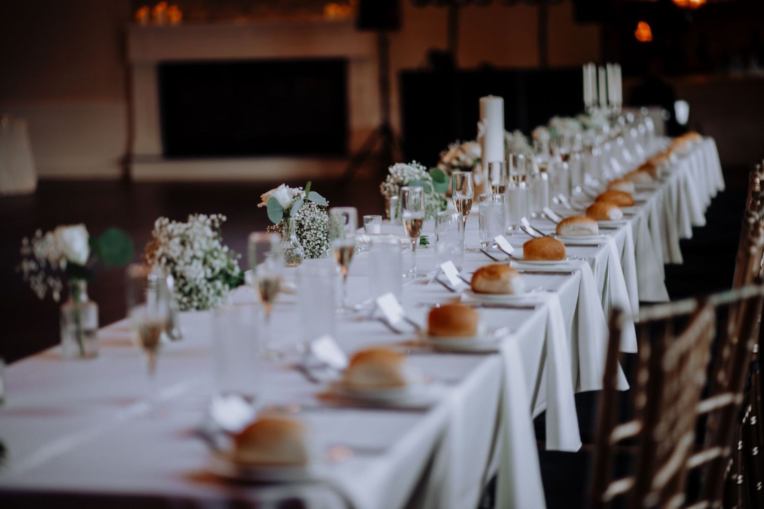 Elegant wedding reception table setting with white linens and floral centerpieces.