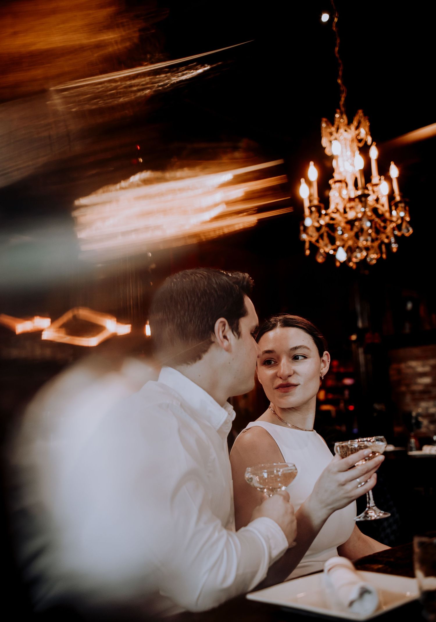 Romantic evening at an upscale bar with crystal chandelier and champagne glasses.