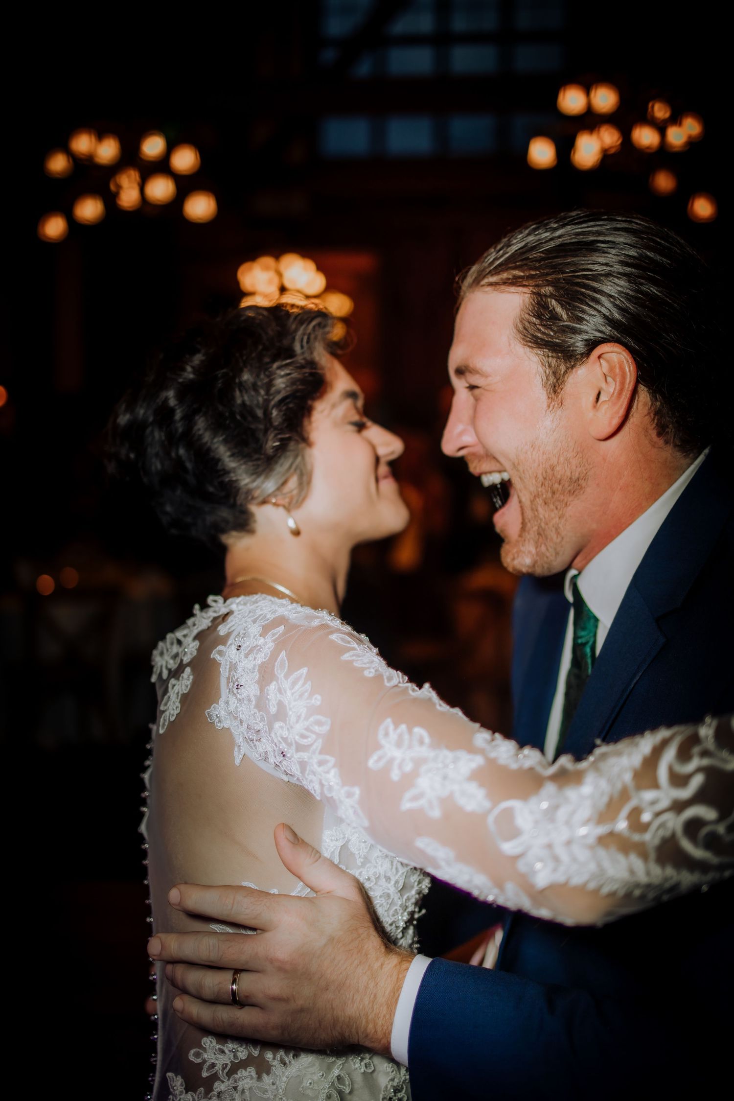 A romantic first dance between newlyweds in an intimate, dimly lit setting with soft glowing lights.