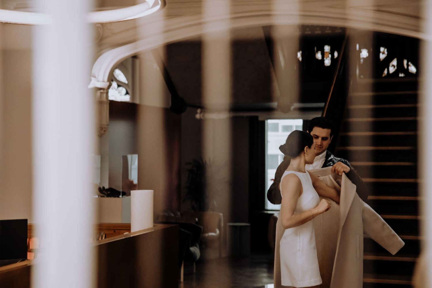 A couple embraces in a grand hallway with ornate architectural details.