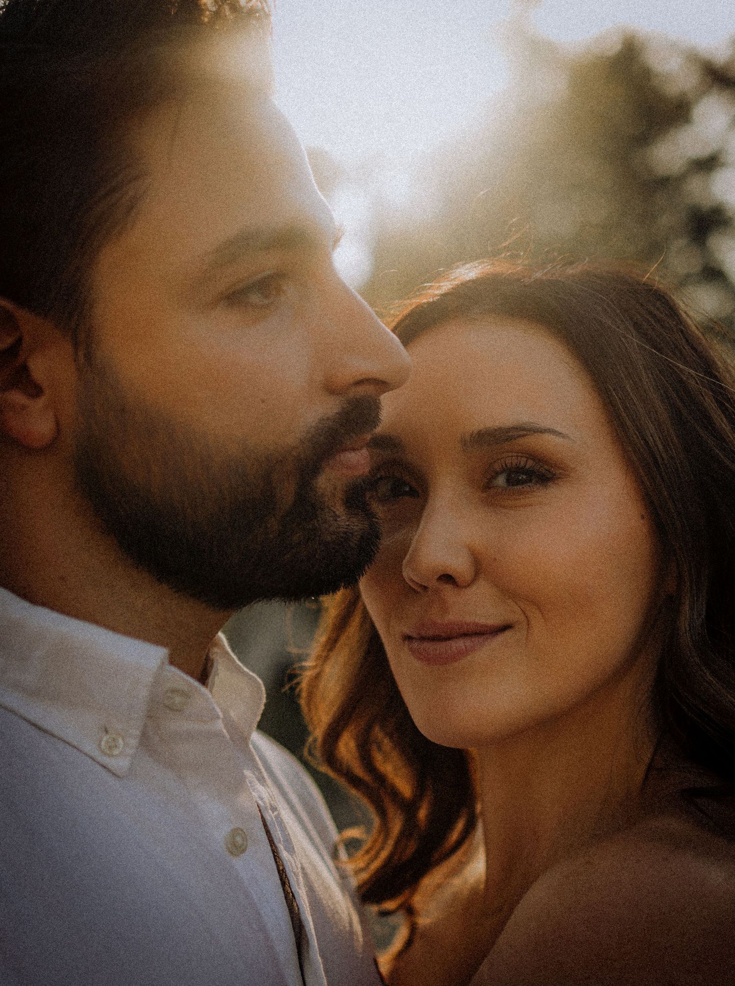 Intimate close-up portrait of couple sharing tender moment in warm sunlight.