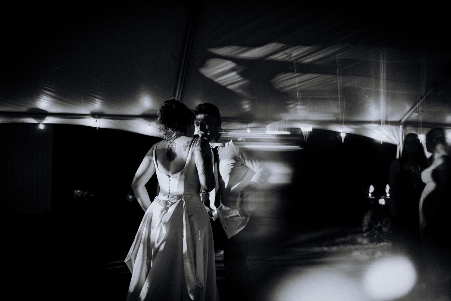 Black and white wedding photos showing intimate moments in a dimly lit reception space.