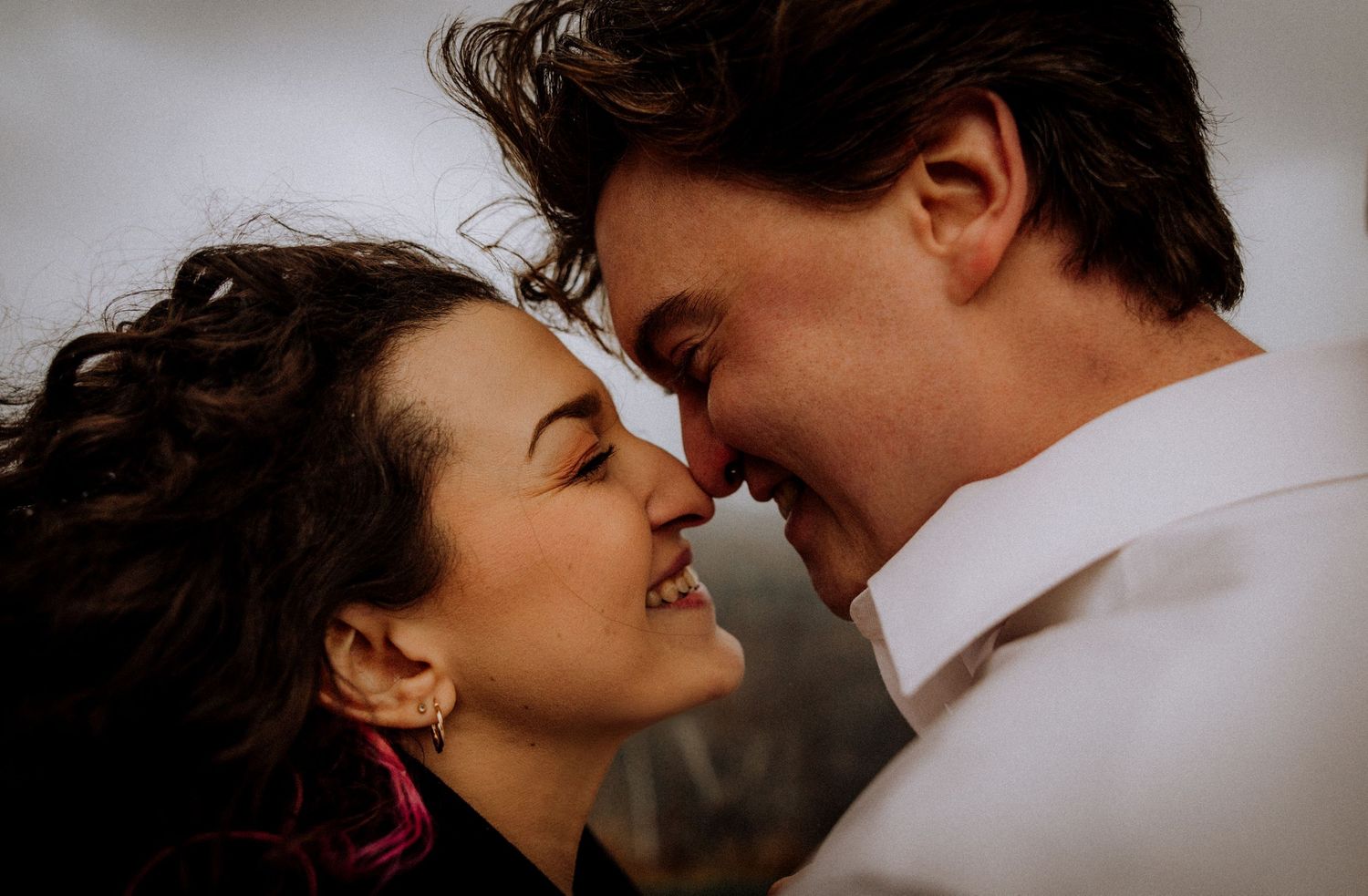 A romantic couple shares an intimate moment against a moody background.