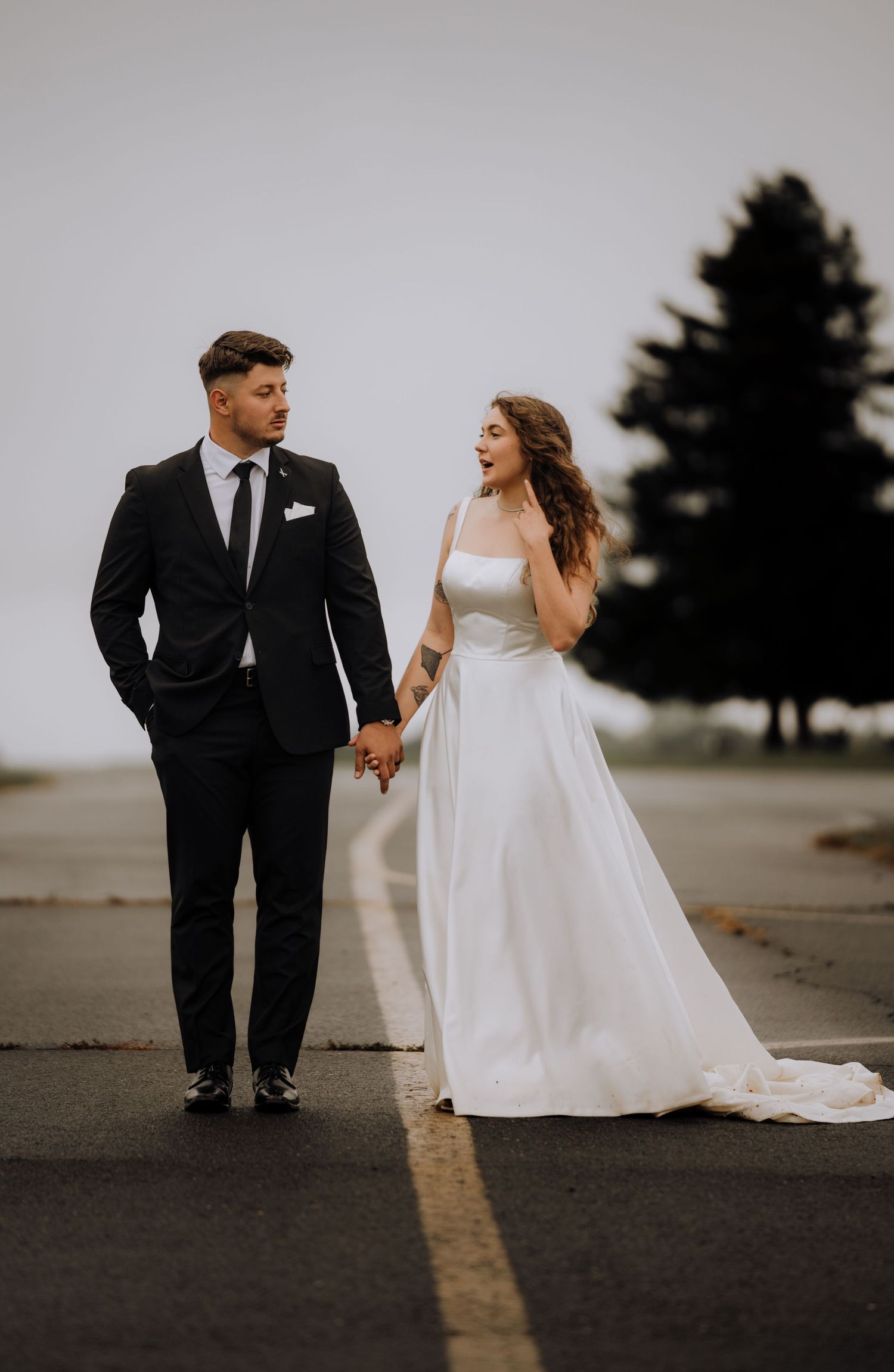 Couple walking and laughing together on a paved path during wedding photos.
