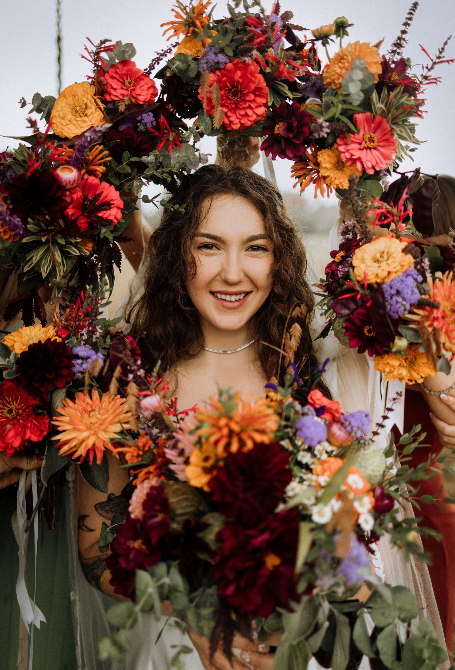 Vibrant autumn floral crown with red, orange and purple blooms.