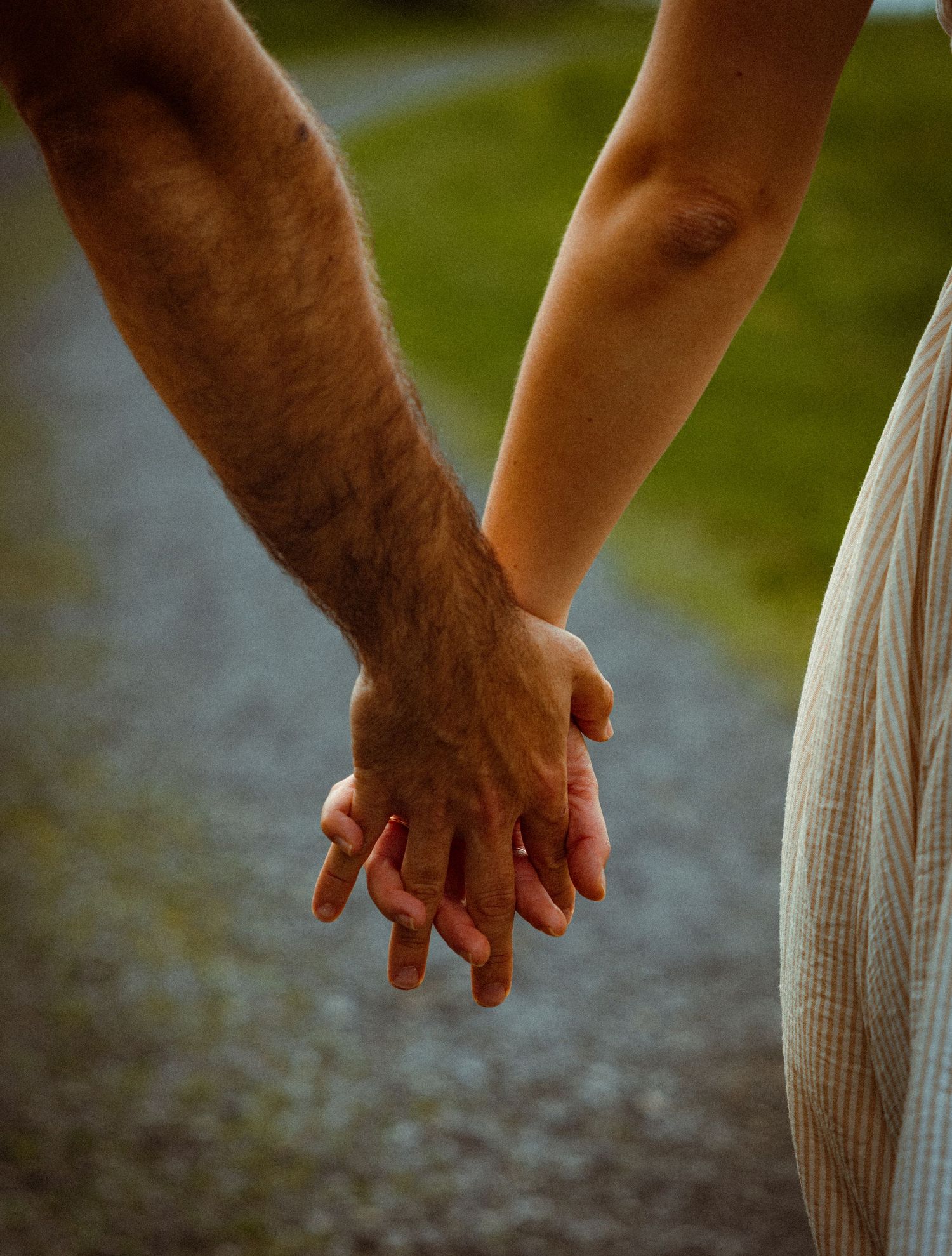 Close-up of hands reaching for each other against a blurred green background.