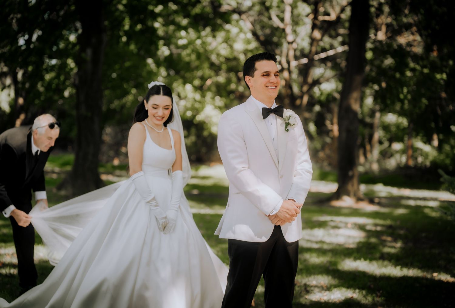 A joyful wedding couple shares intimate moments in a sun-dappled outdoor garden setting.