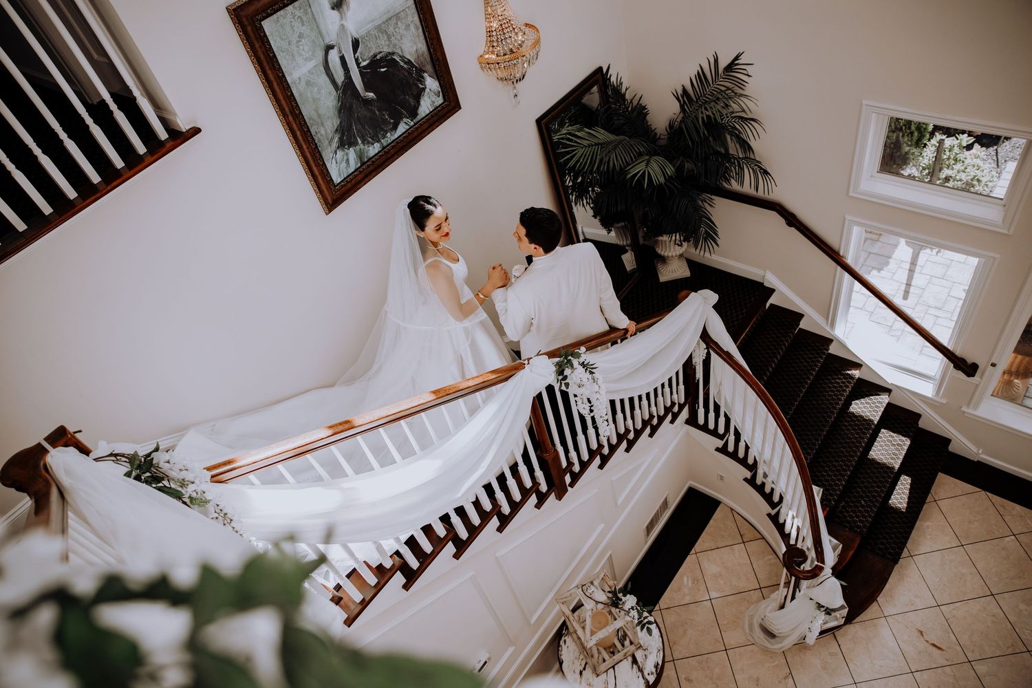 Wedding couple photographed on an elegant staircase with framed artwork.