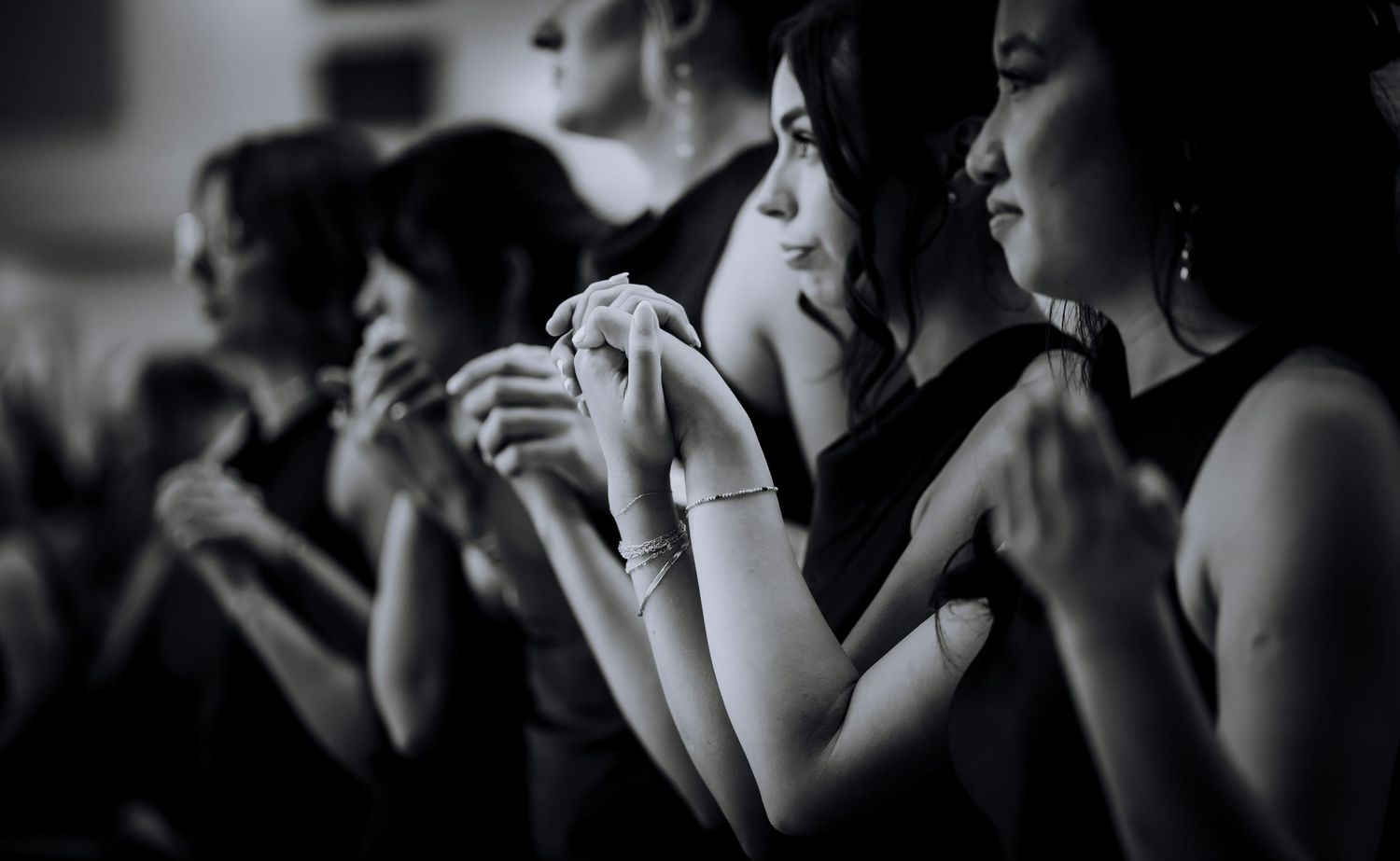 Wedding guests watch emotionally during a ceremony in black and white photography.