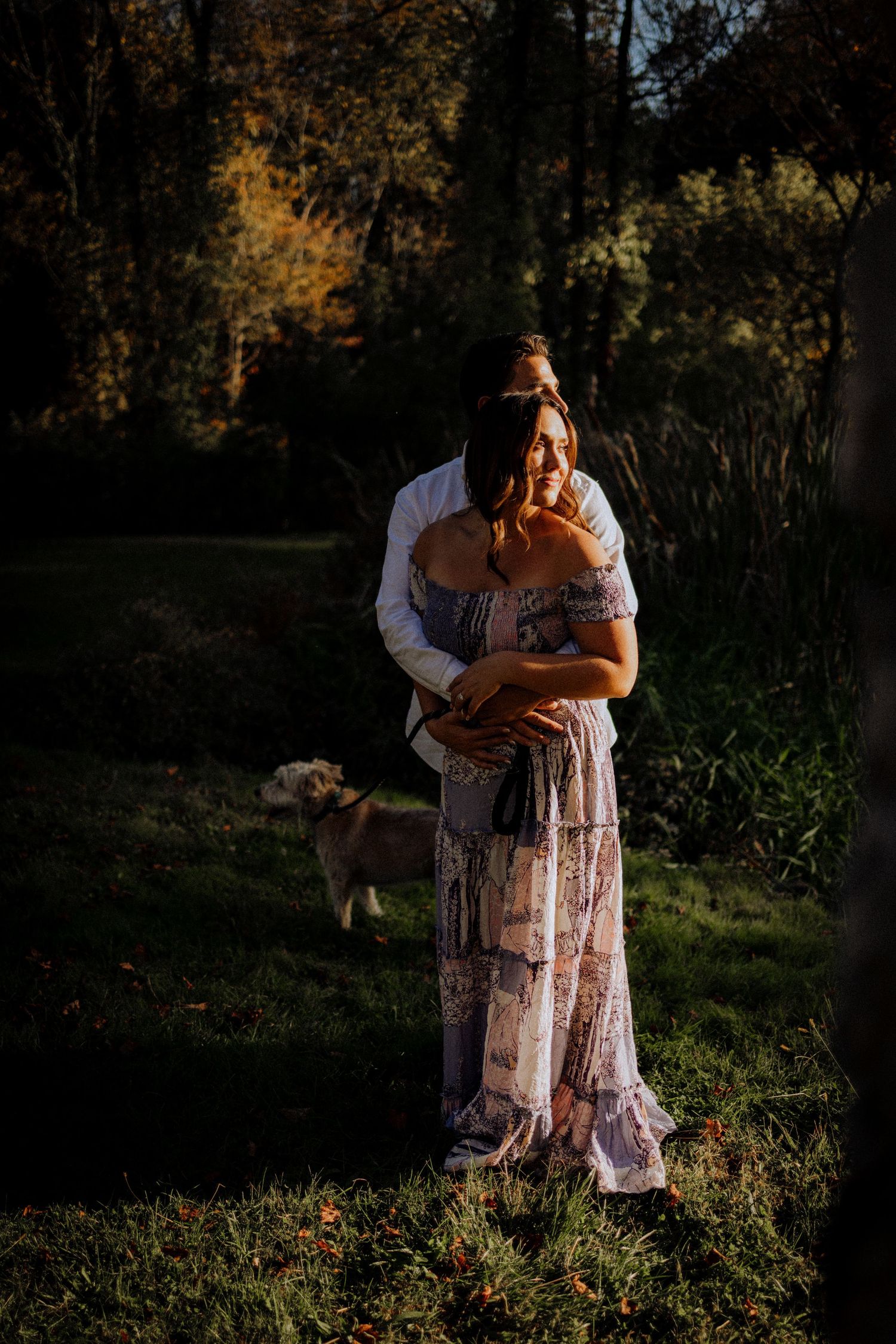 Romantic couple embracing in a sunlit meadow during golden hour.