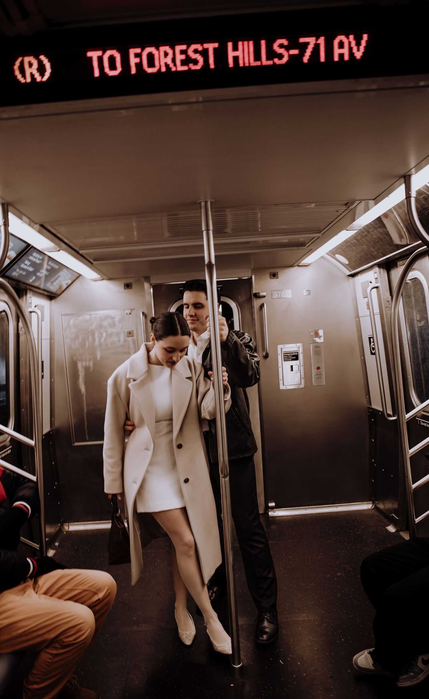 A subway car interior with 'To Forest Hills' sign in red neon lighting.