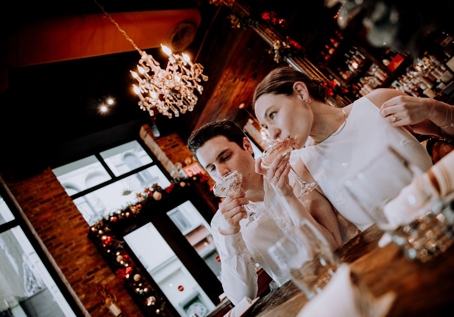 Couple enjoying drinks at an upscale bar under ornate crystal chandeliers.