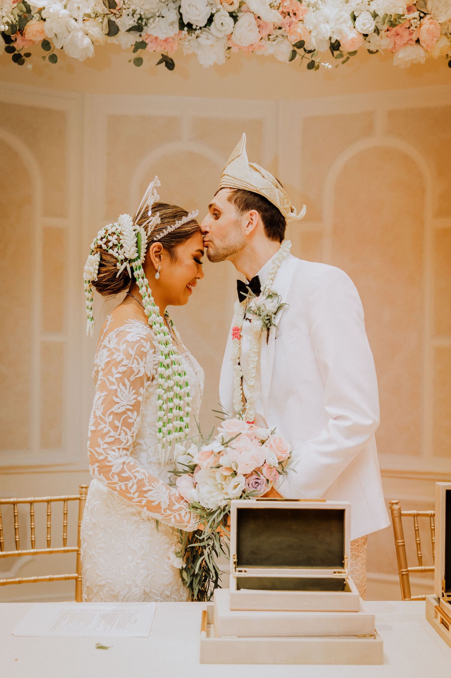 A romantic wedding moment captured under floral decor with vintage decor and soft peach lighting.