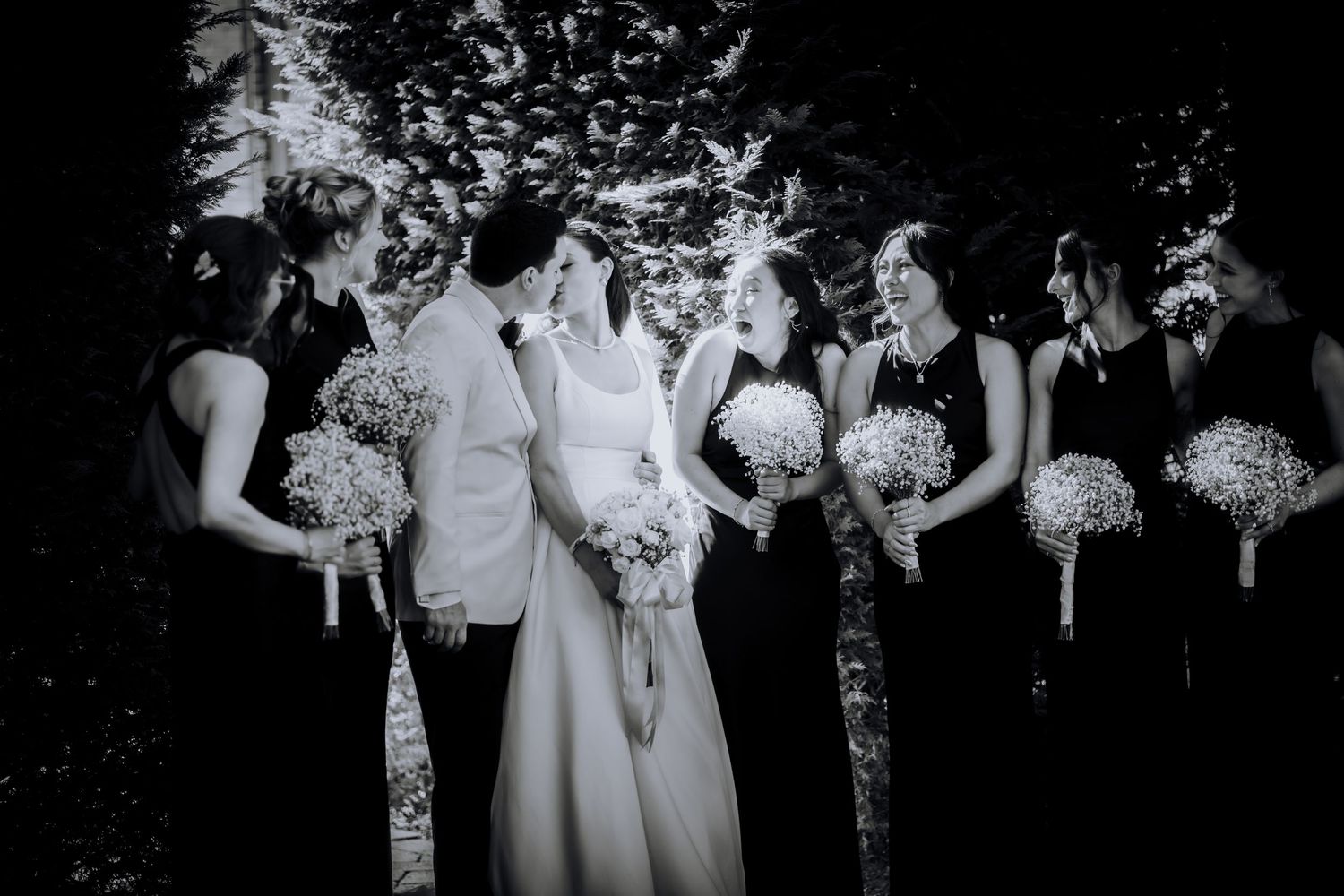 Wedding party members holding bouquets in an elegant black and white photograph.