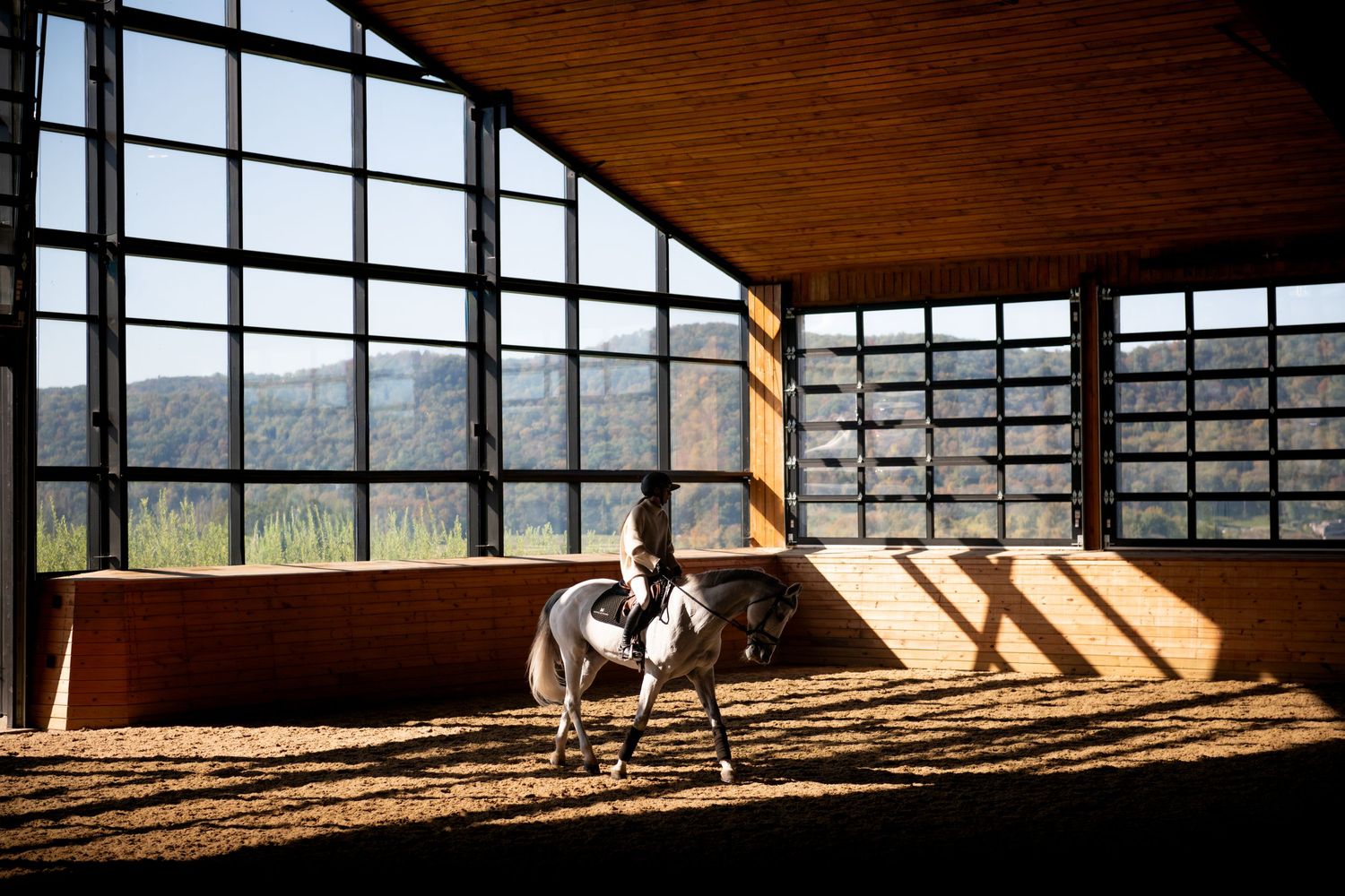 Sunlight streams through glass garage doors in an empty industrial warehouse space creating dramatic shadows.