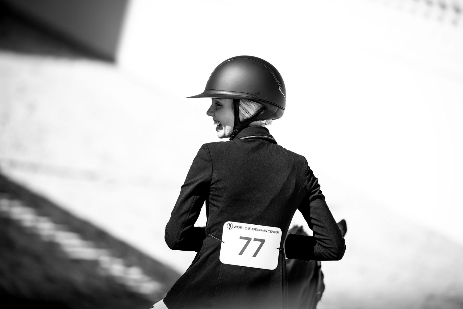 Equestrian rider wearing a helmet and competition number 77 during a horseback riding event.