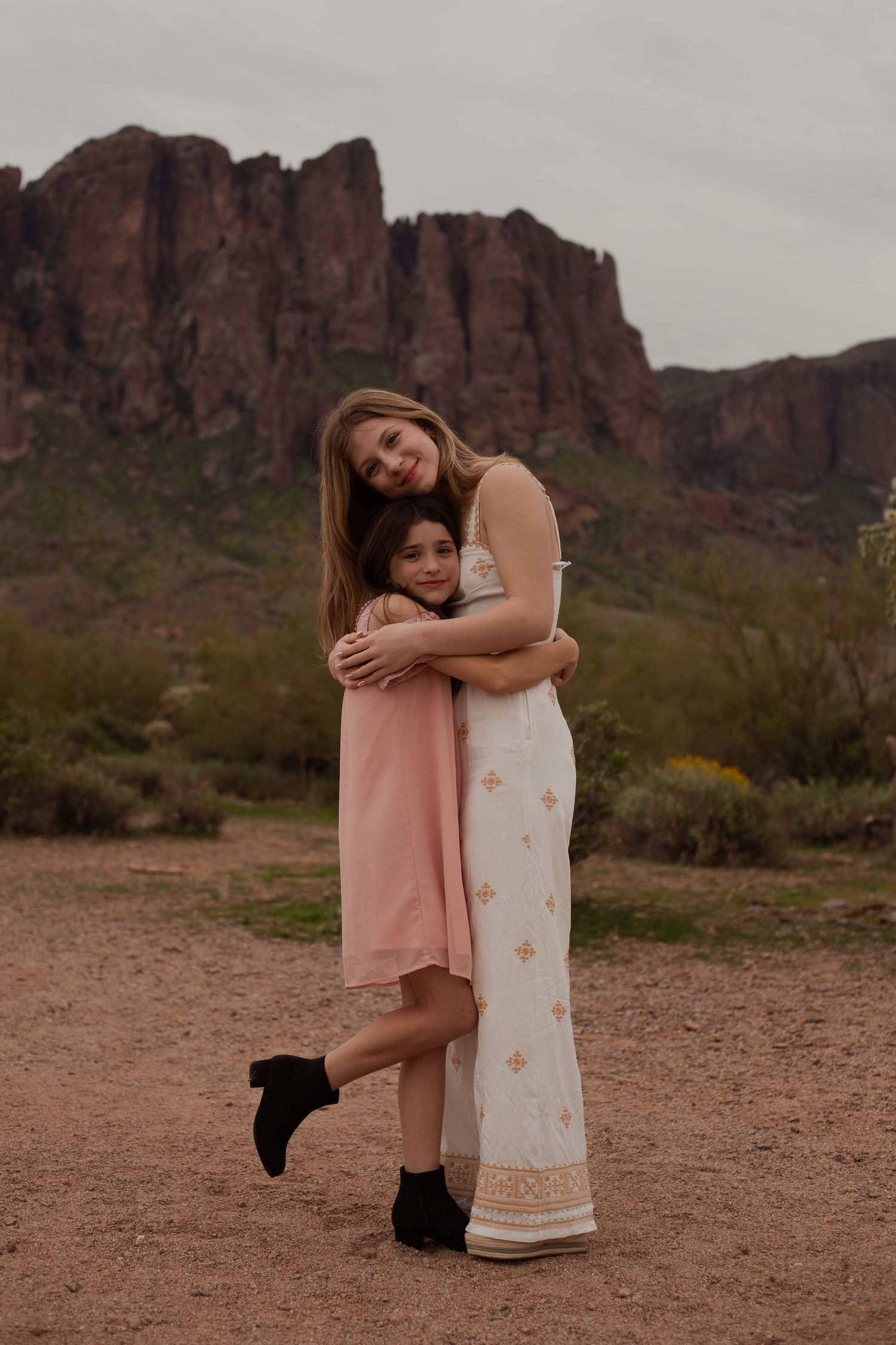 Sisters hugging in desert landscape in Phoenix AZ