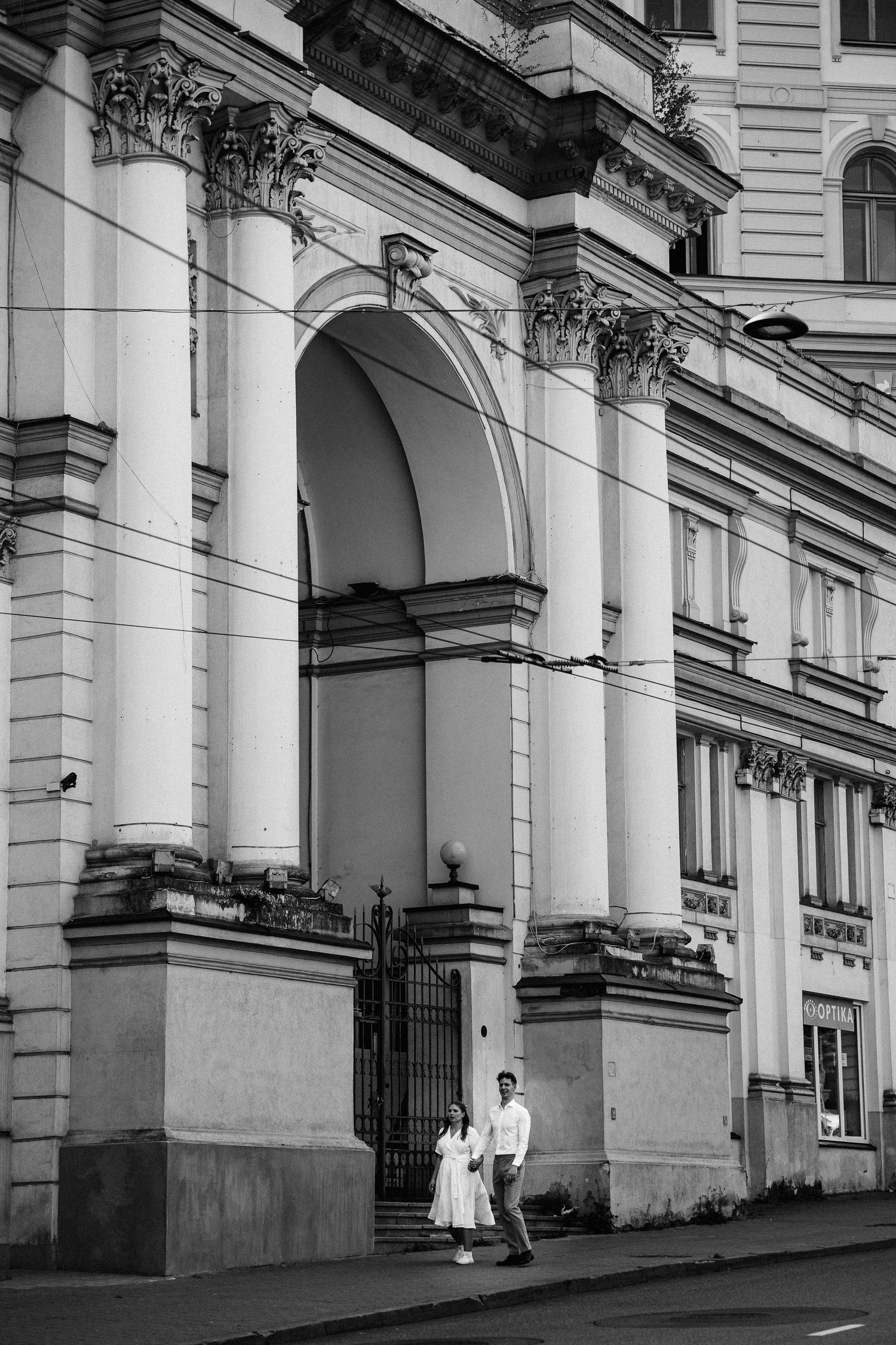 Jaunieji eina gatve priešais pastatą Vilniuje