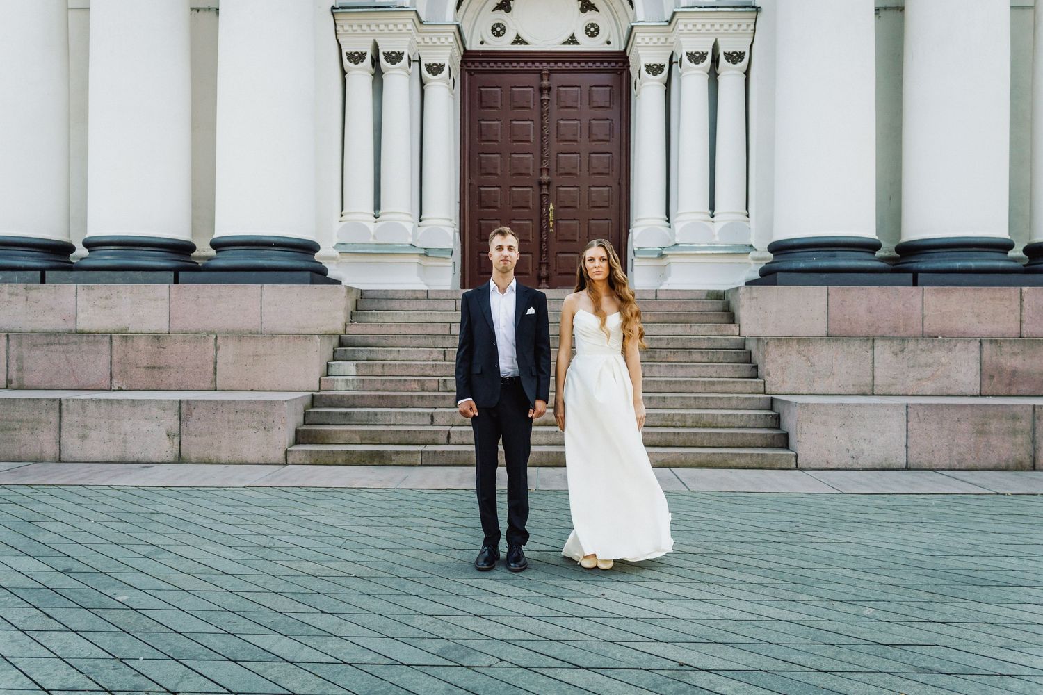 Jaunavedžiai stovi priešais Kauno Soboro Bažnyčia, laimingi ir pasiruošę savo vestuvių ceremonijai