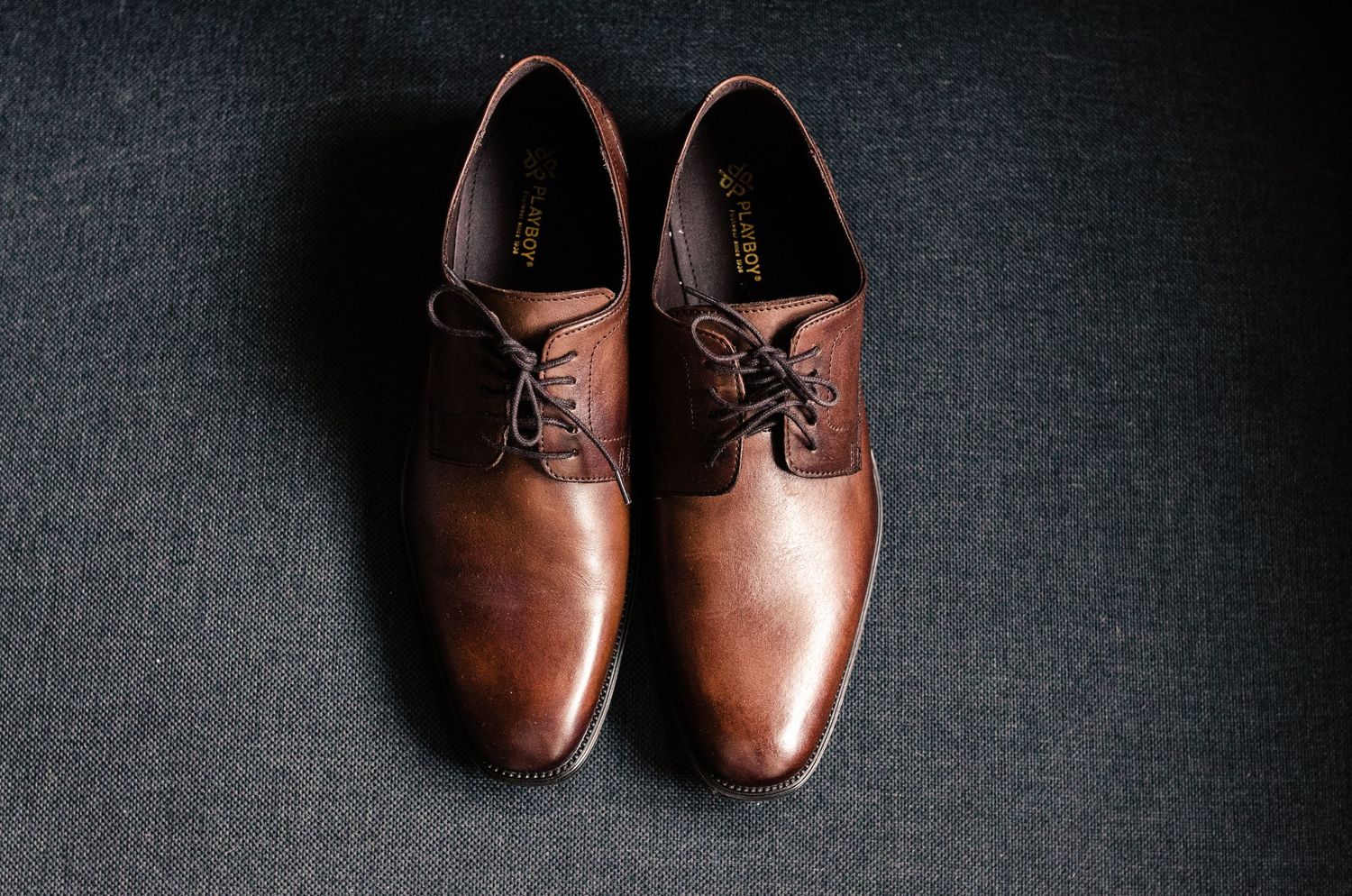 Brown leather dress shoes photographed on dark background.