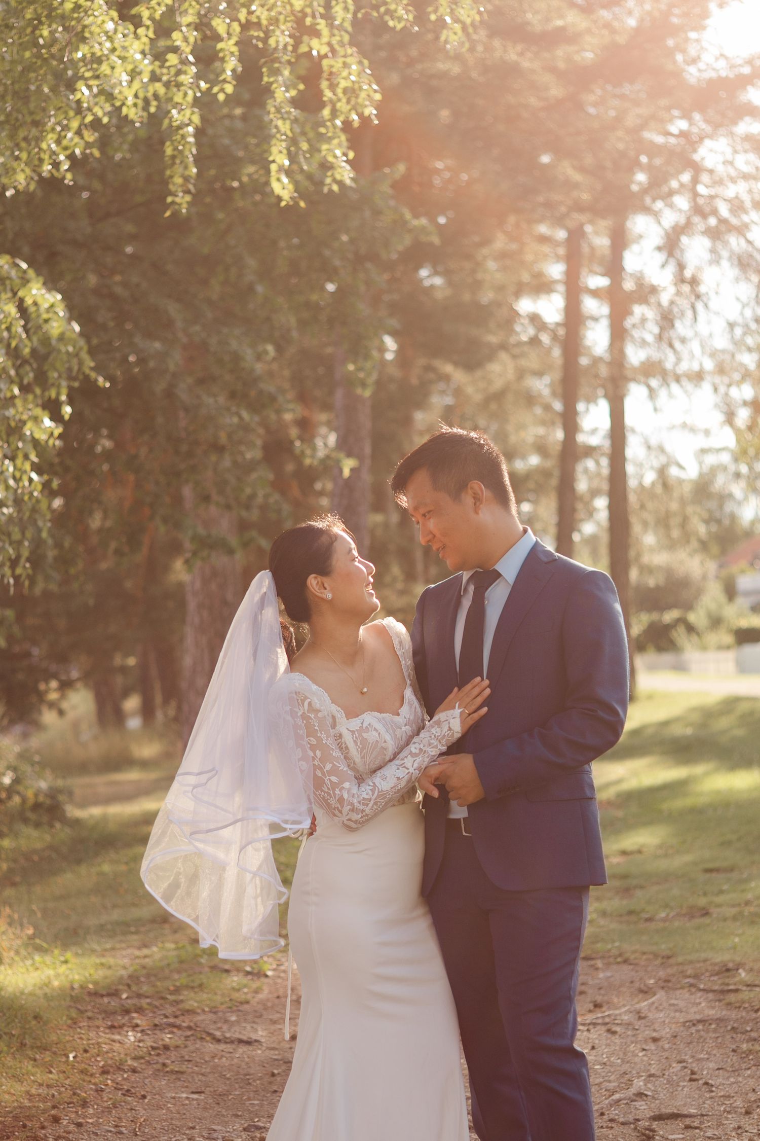 A couple shares romantic moments in golden sunlight under forest trees.