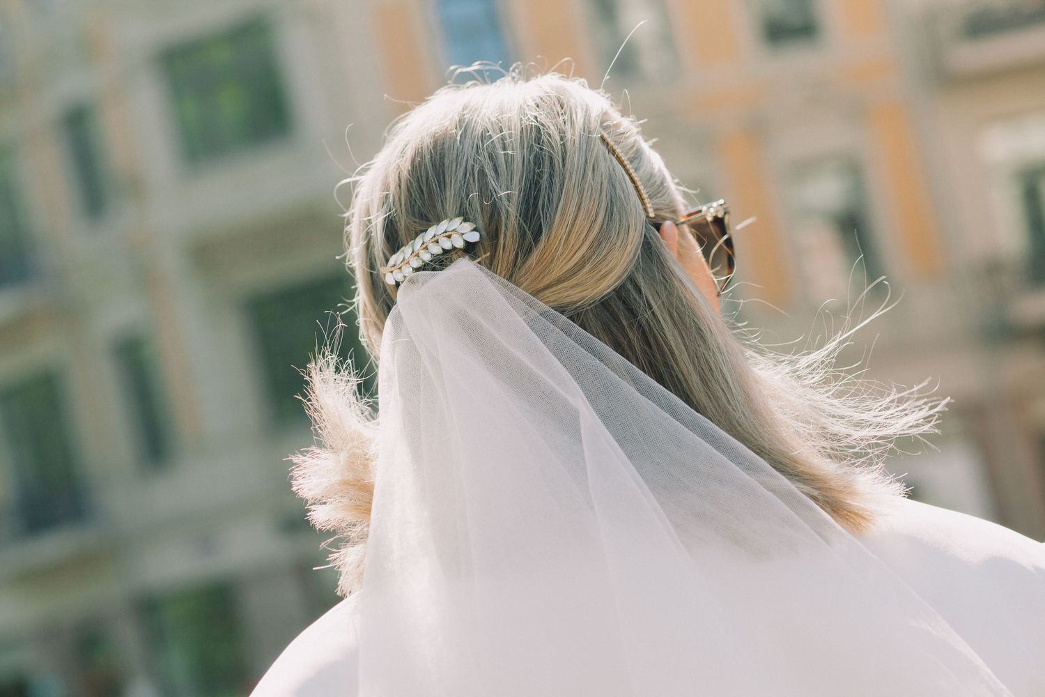 Close-up shots of a bride's veil flowing in the breeze against an architectural backdrop.