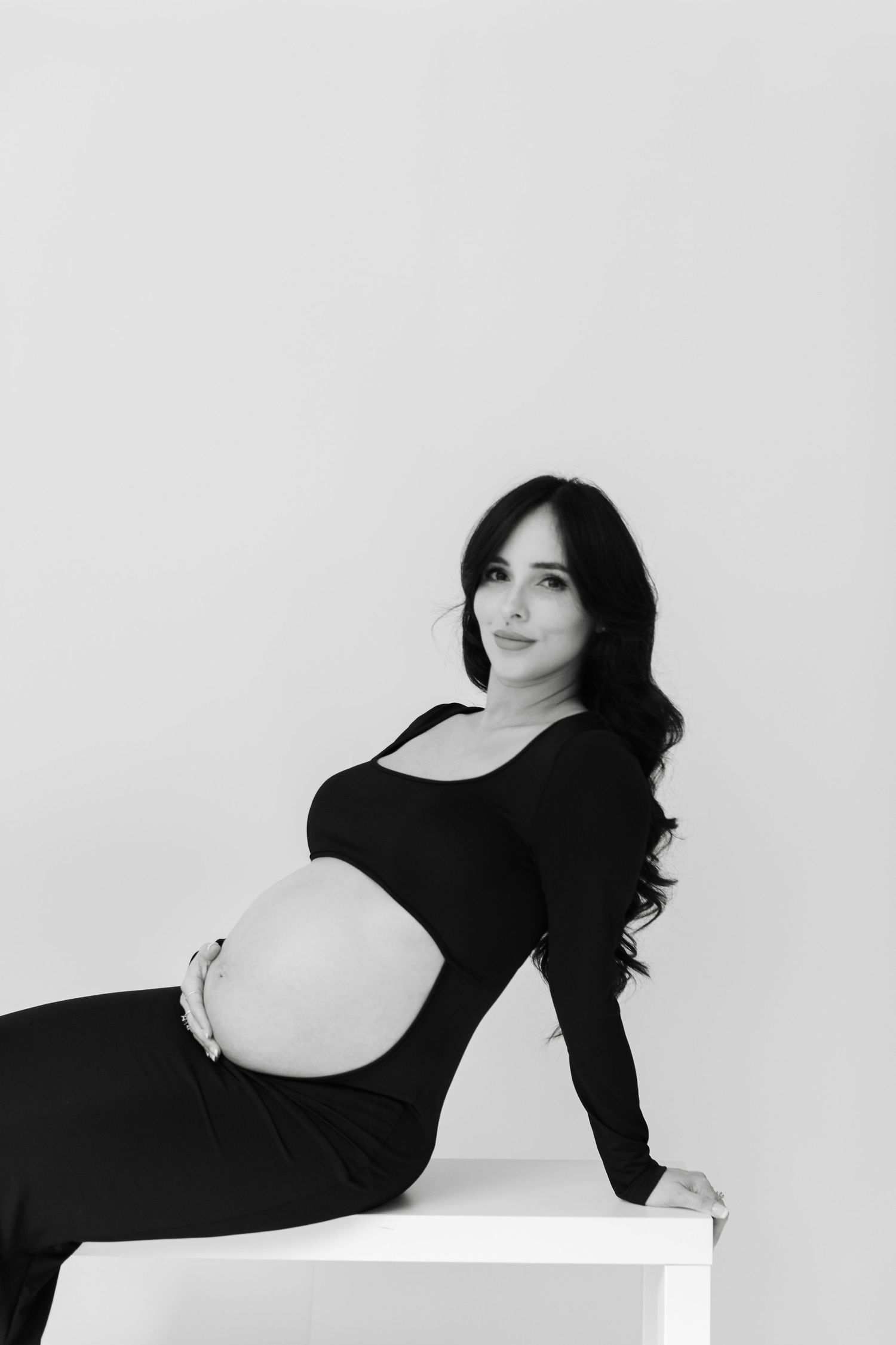 Artistic black and white portrait series of a person in dark clothing posing against a white background.