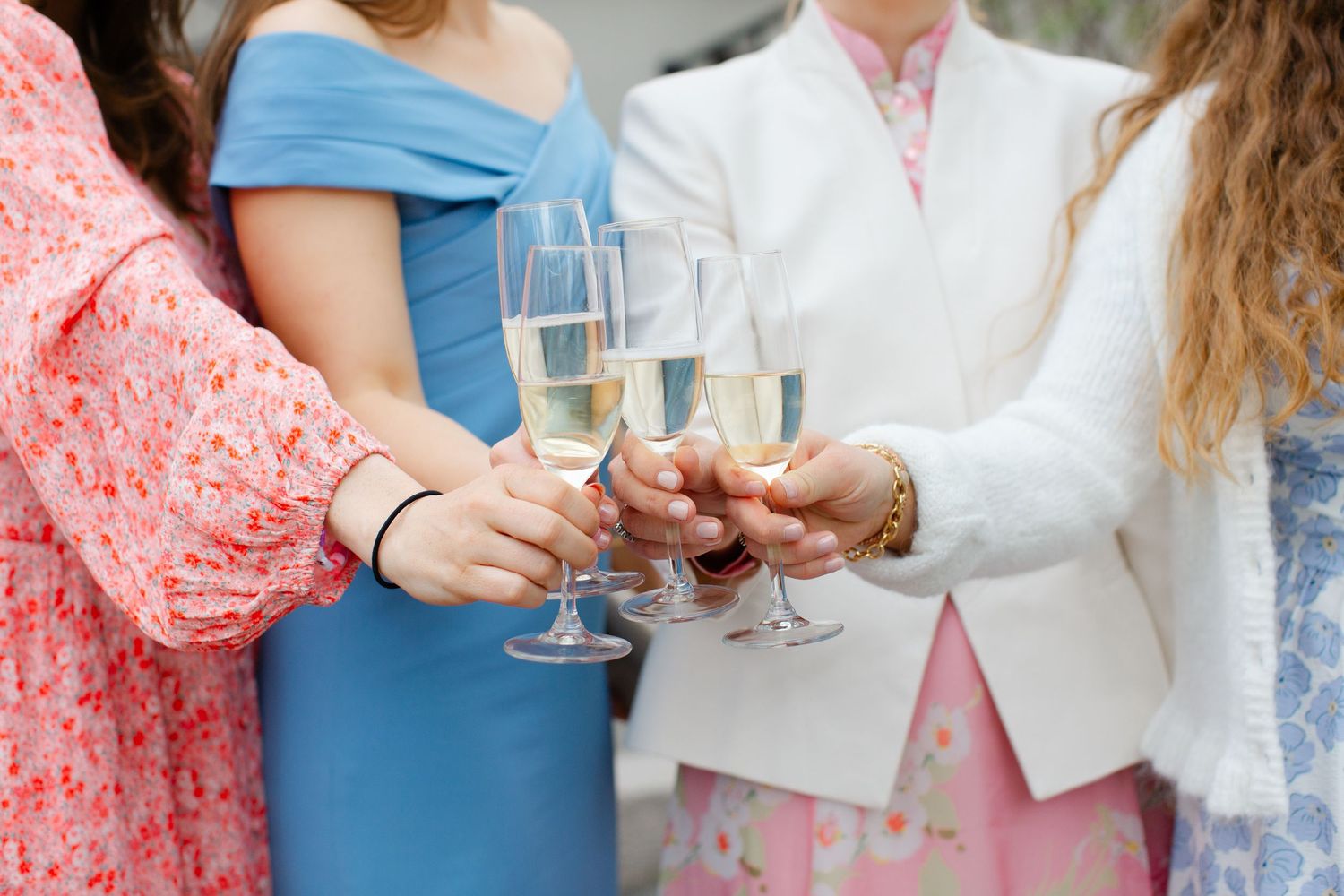 Wedding guests toasting with champagne flutes in colorful formal attire.