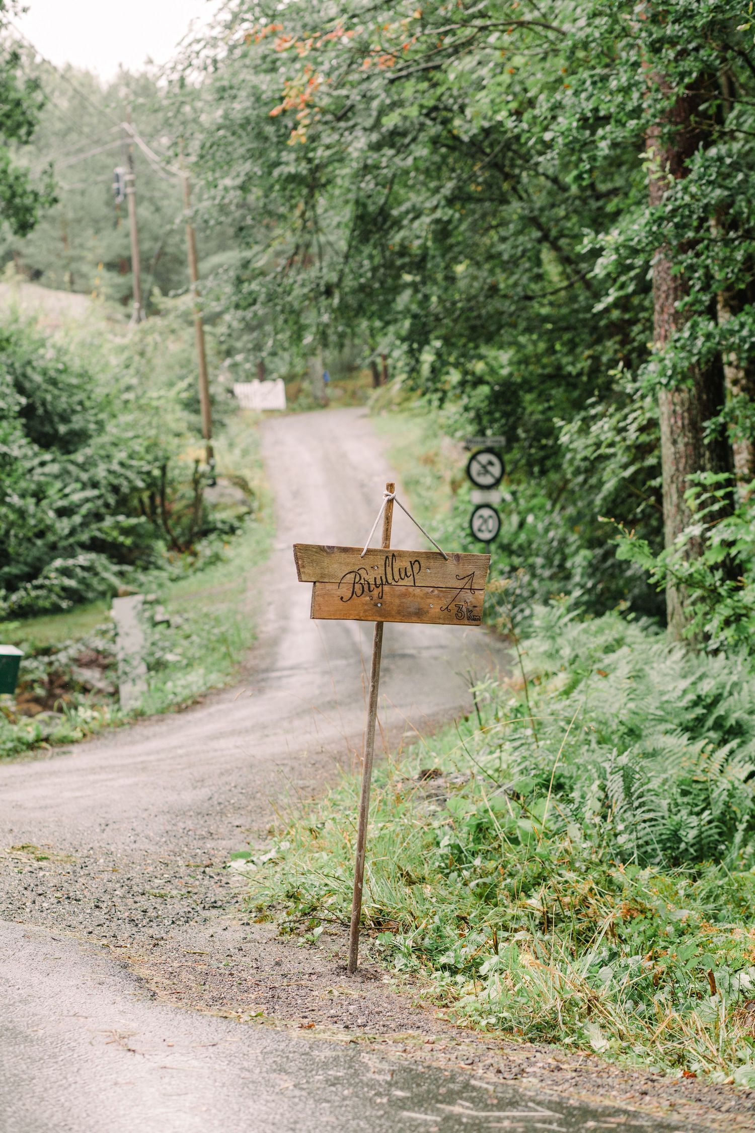 Wooden directional signs on gravel path through wooded area.